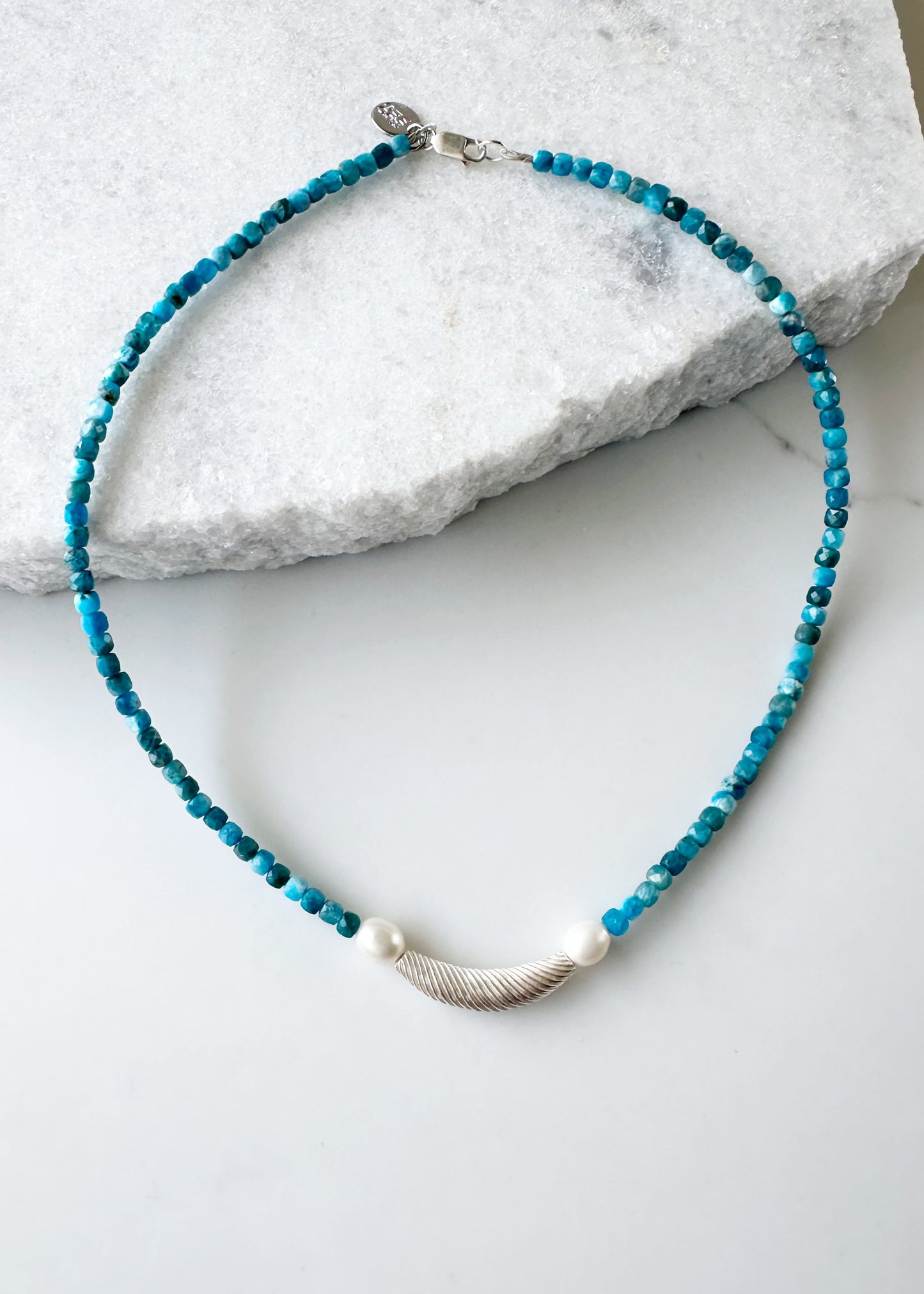 This One-Of-A-Kind 18.5” Necklace Features a Textured Silver Bead Surrounded by White Freshwater Pearls and Beautiful Blue Faceted Apatite Cubes.  Designed and Made in Canada, this piece is Finished with a Sterling Silver Lobster Claw Clasp.