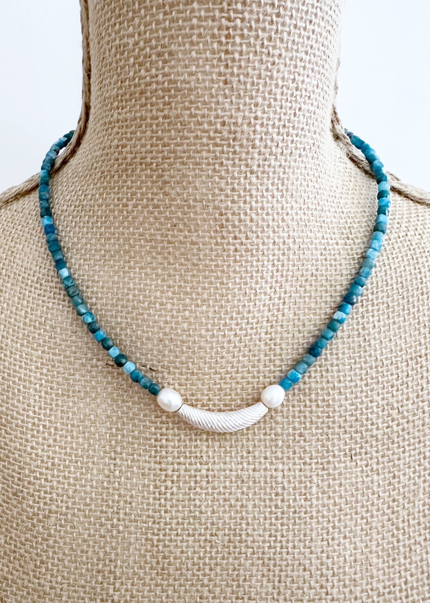 This One-Of-A-Kind 18.5” Necklace Features a Textured Silver Bead Surrounded by White Freshwater Pearls and Beautiful Blue Faceted Apatite Cubes.  Designed and Made in Canada, this piece is Finished with a Sterling Silver Lobster Claw Clasp.