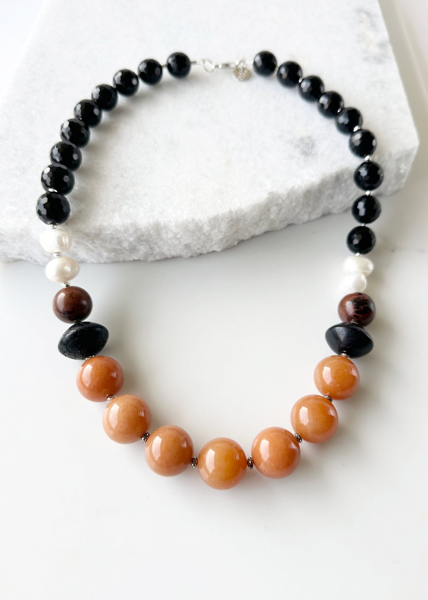 This One-Of-A-Kind 22.5” Necklace Features Large, Round, Orange Aventurine, Black Agate, Mahogany Obsidian and Pearls, Accented with Silver and Finished with a Sterling Silver Lobster Claw Clasp.