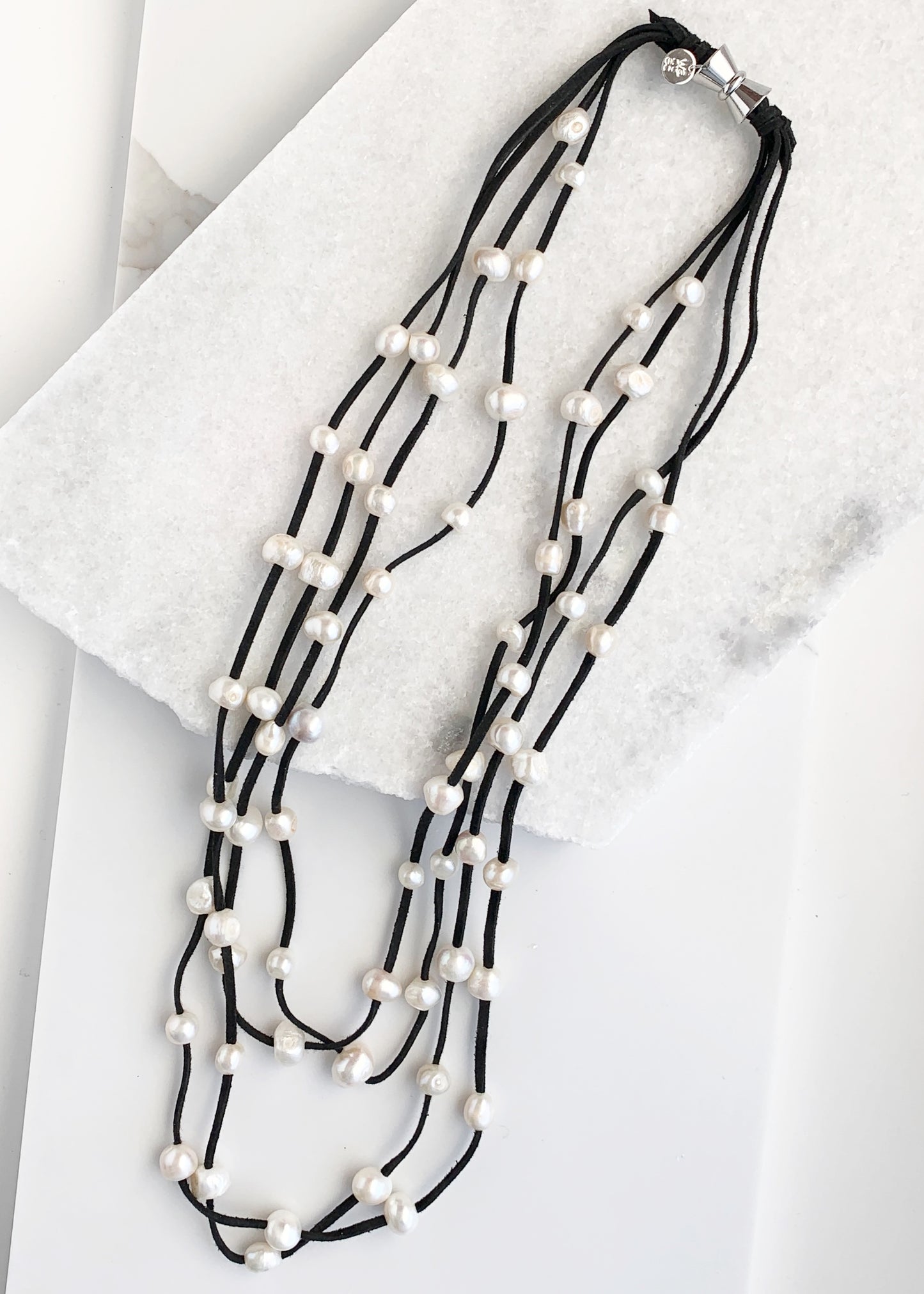 Four Strand Freshwater Pearl Necklace showing White Pearls Staggered on Black Vegan Suede.  A Strong, Secure Magnetic Clasp Makes this Easy to Put on and Take off.