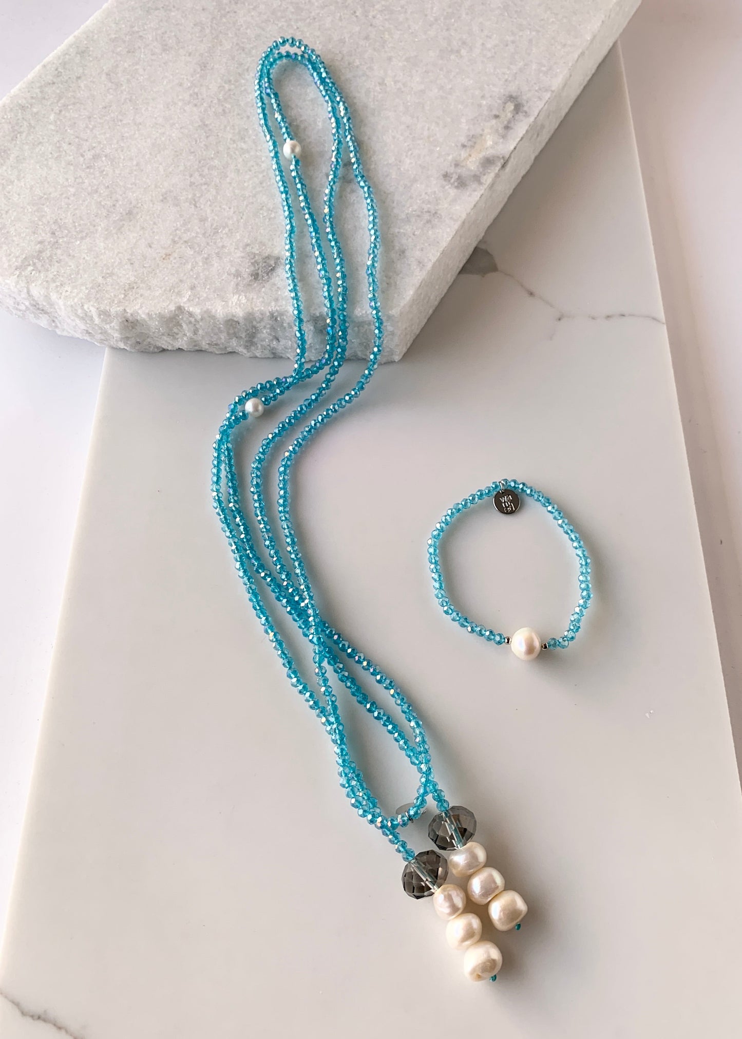 Long, 64-inch Lariat-Style Necklace with Blue Crystals and White Freshwater Pearls.  This Versatile piece allows it to be worn in many ways. Shown with matching Bracelet