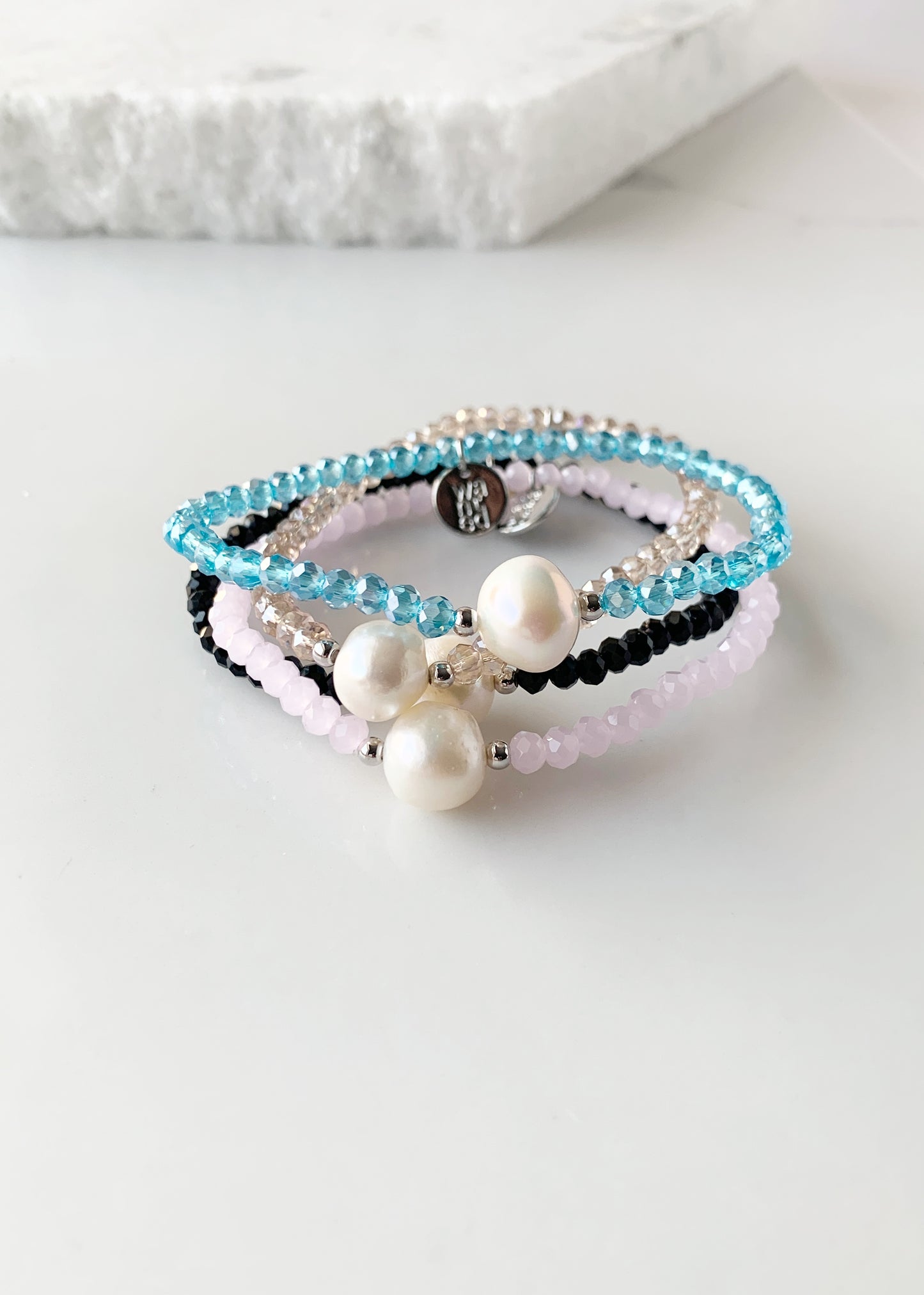 Shown are All Four Colors of Faceted Crystal Bracelet with Large White Pearl Centered between two Silver Beads. Stacked on Top of each other.