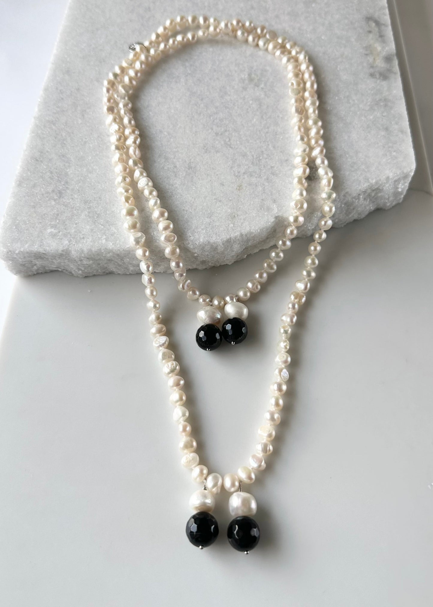 Long Generous White Freshwater Pearl Necklace with Larger Pearl and Black Agate drops.  Can be worn in many Styles.