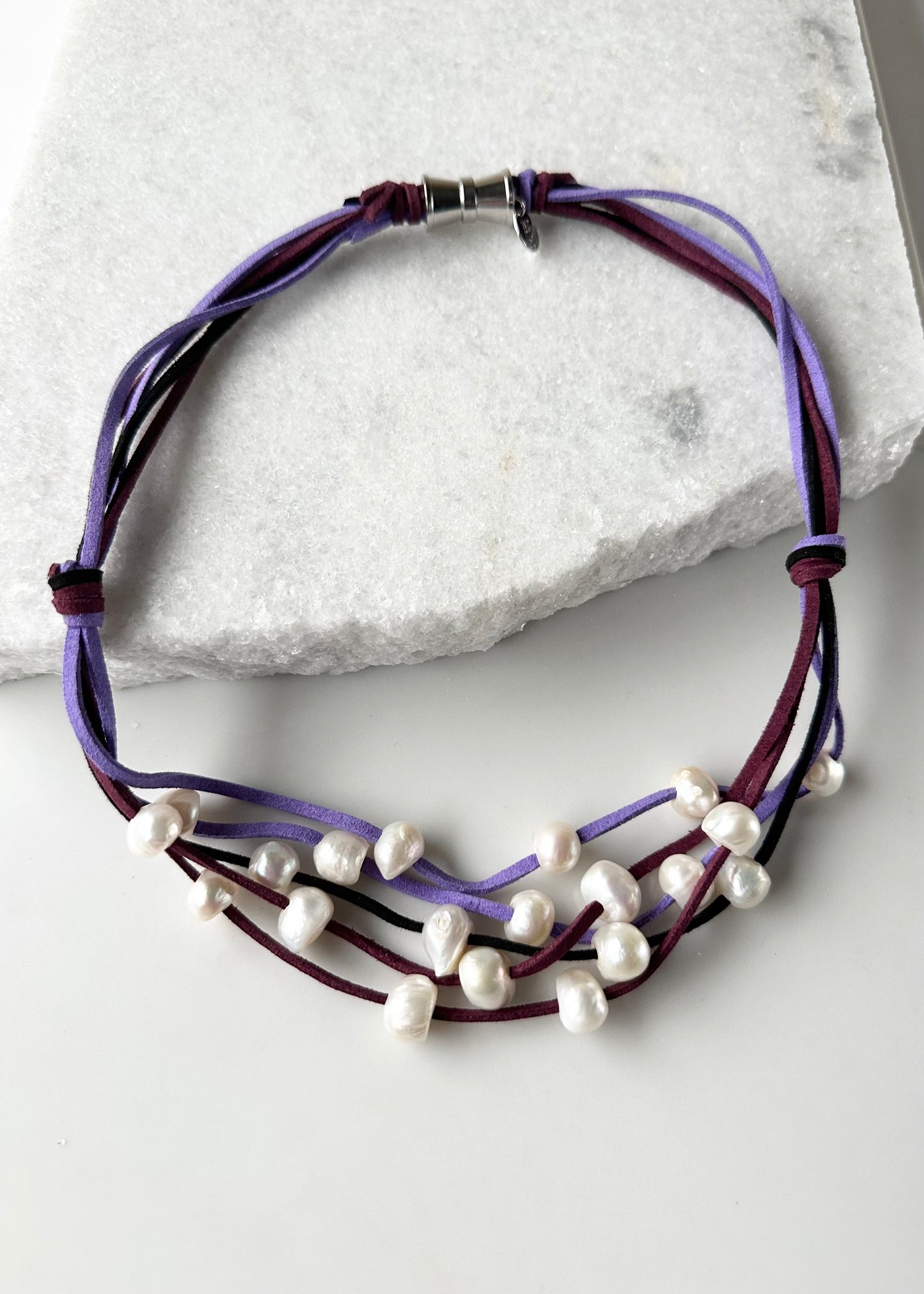 Five Strands of Purple Vegan Suede with Floating White Freshwater Pearls are Offered with a Strong Secure Magnetic Clasp for Easy Wear.