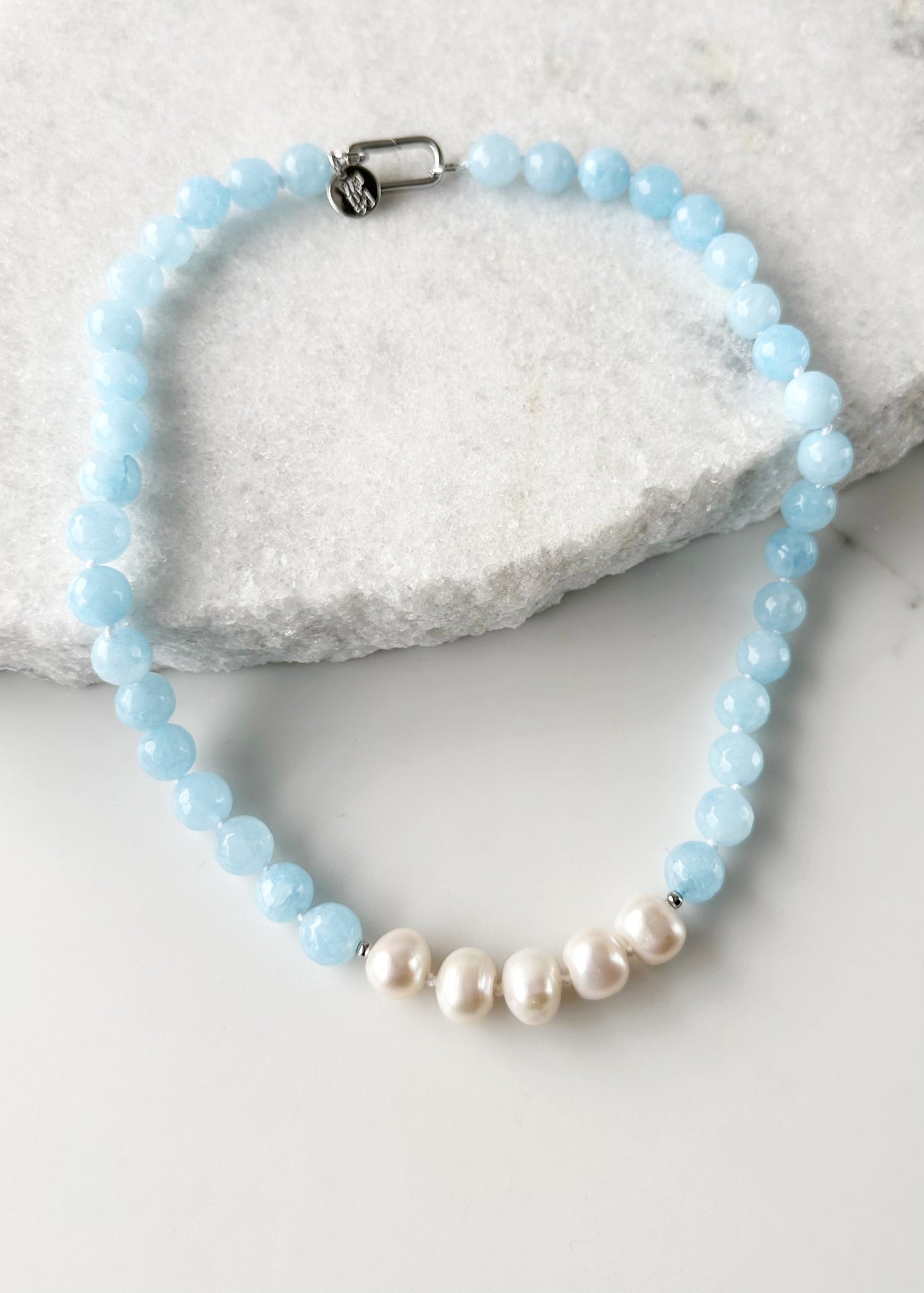 White Freshwater Baroque Pearls Strung with Faceted White or Blue Semi-Precious Stones with a Pretty Carved Shell Flower Pendant Hanging from a Gold-Plated Rectangular Clasp for a 18.5” Necklace.  This Necklace can be worn in Various ways. Shown without Pendant.