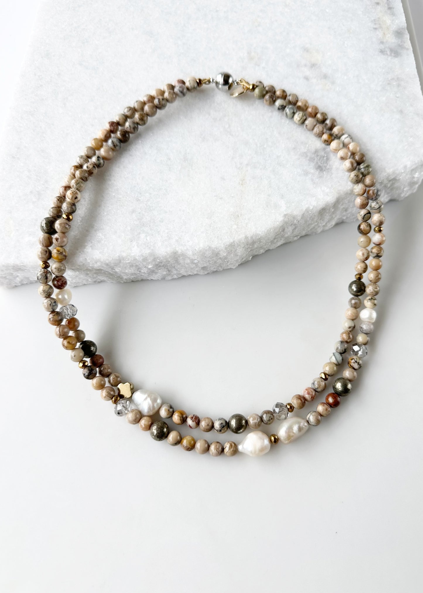 This Two-Strand (Inner Length of 19”) Necklace Features White African Opal and Freshwater Pearls Accented with Pyrite, Faceted Crystal and Gold-Plated Hematite for a soft elegant touch. Finished with a Magnetic Clasp for Easy Wear. Designed and made in Canada