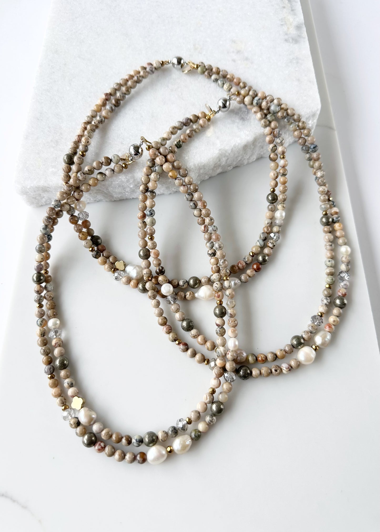 This Two-Strand (Inner Length of 19”) Necklace Features White African Opal and Freshwater Pearls Accented with Pyrite, Faceted Crystal and Gold-Plated Hematite for a soft elegant touch. Finished with a Magnetic Clasp for Easy Wear. Designed and made in Canada