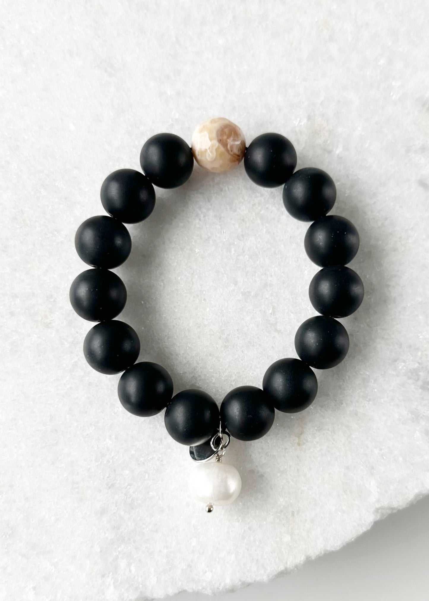 This 7” Stretch Bracelet Features a Large (14mm) Faceted Beige Agate Surrounded by Matte Black Agate with a Freshwater Pearl Dangle. Beautiful on it's own or added to your stack. Designed in Canada