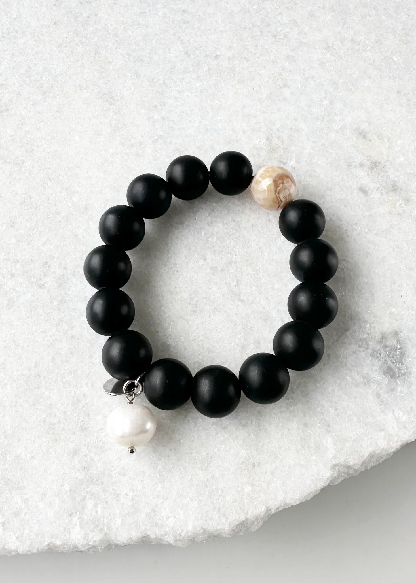 This 7” Stretch Bracelet Features a Large (14mm) Faceted Beige Agate Surrounded by Matte Black Agate with a Freshwater Pearl Dangle. Beautiful on it's own or added to your stack. Designed in Canada
