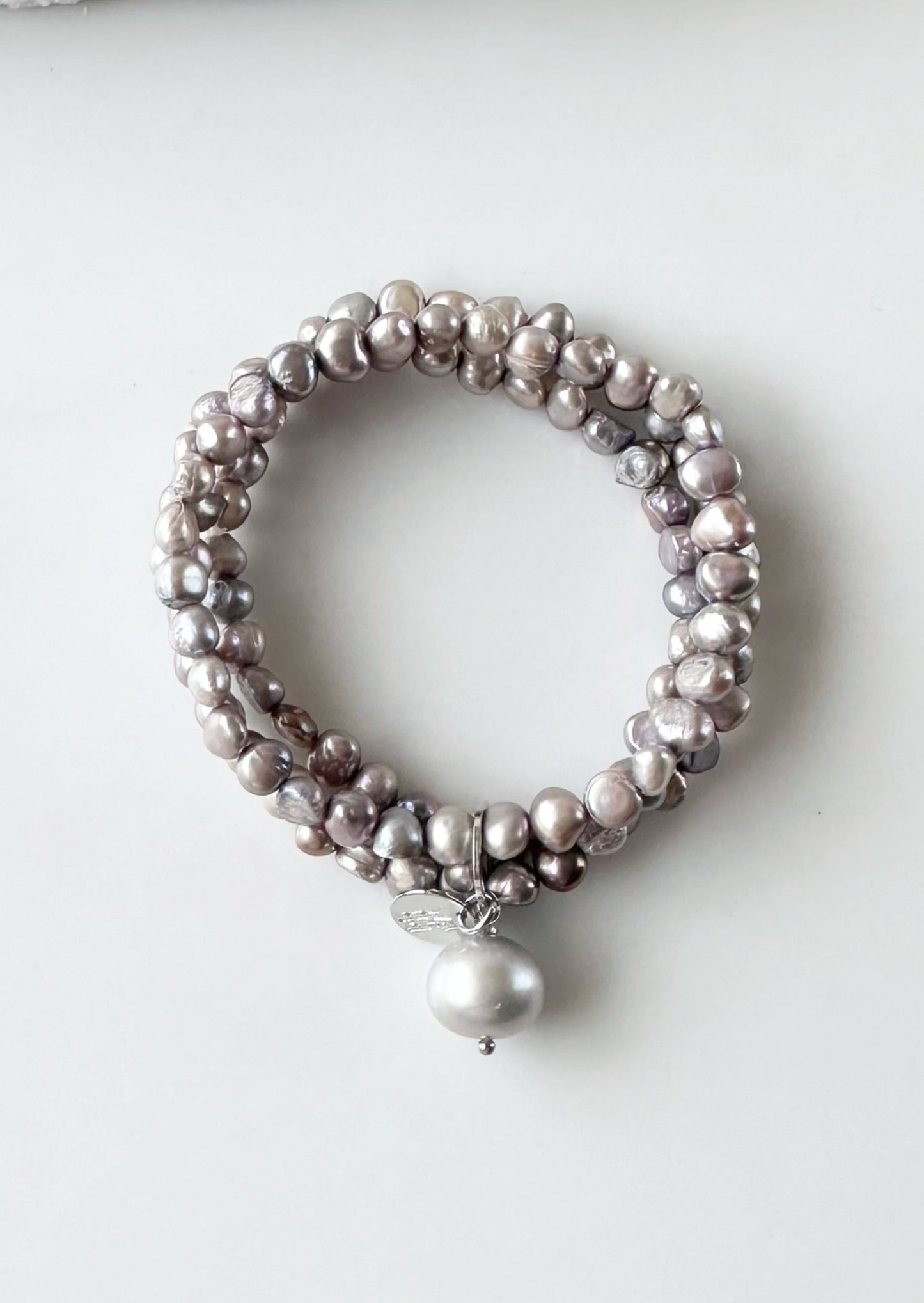 Three Strands of Delicate Silver Baroque Freshwater Pearls with a Large Pearl Dangle form this Pretty Stretch Bracelet.