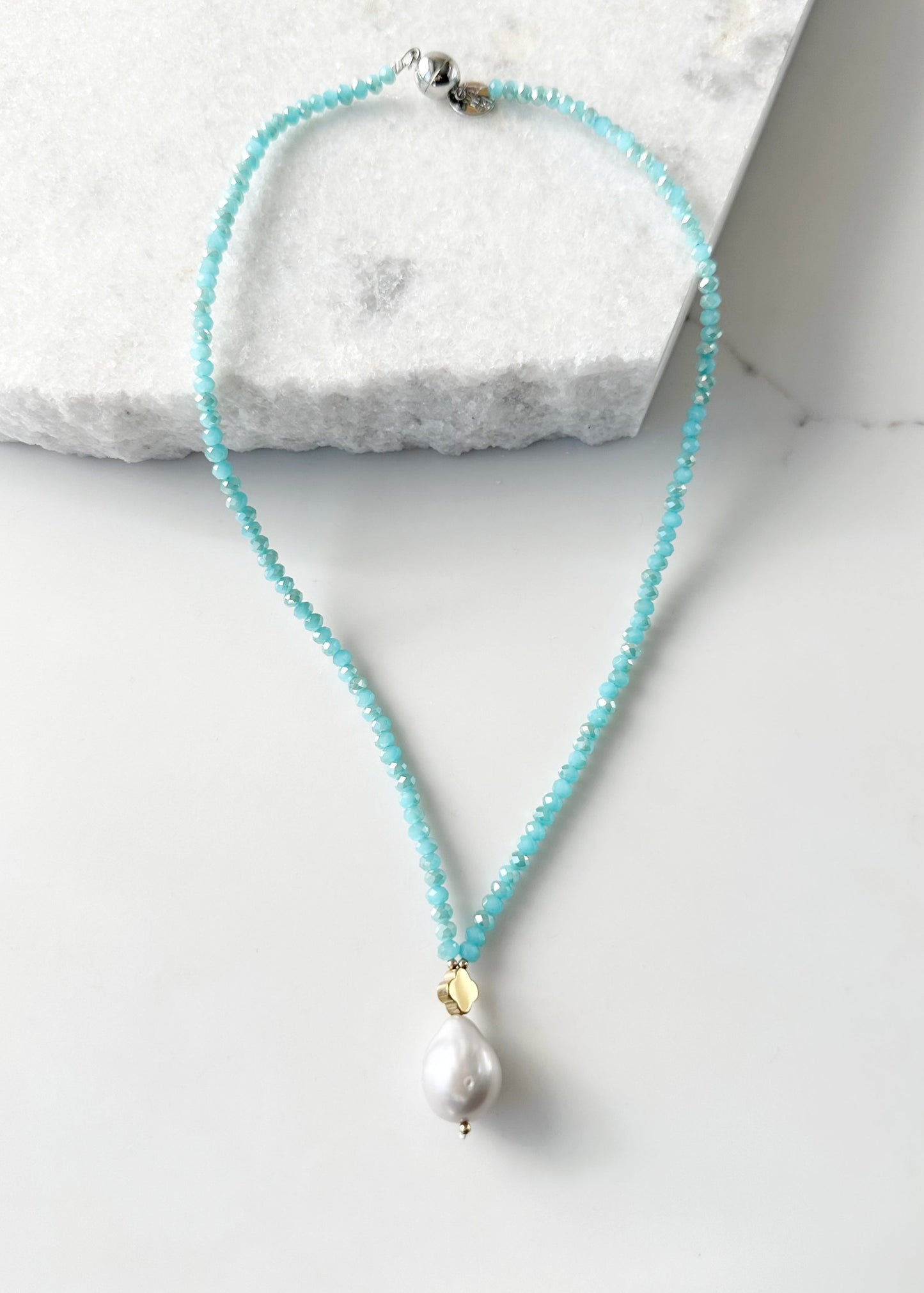 Faceted Blue Crystals form this Necklace with a Large White Baroque Freshwater Pearl Pendant Completed with Gold accents and a Strong Secure Magnetic Clasp for East Wear.