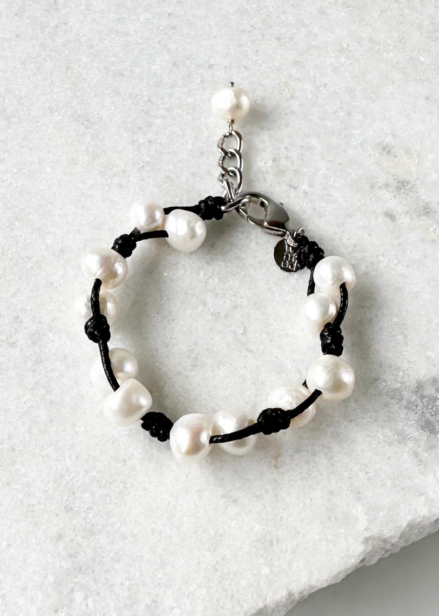 This 7.5” Bracelet Features Lustrous Freshwater Pearls Knotted on Cotton Cord,  Completed with a Large Lobster Claw Clasp and Extender Chain. Designed in Canada.