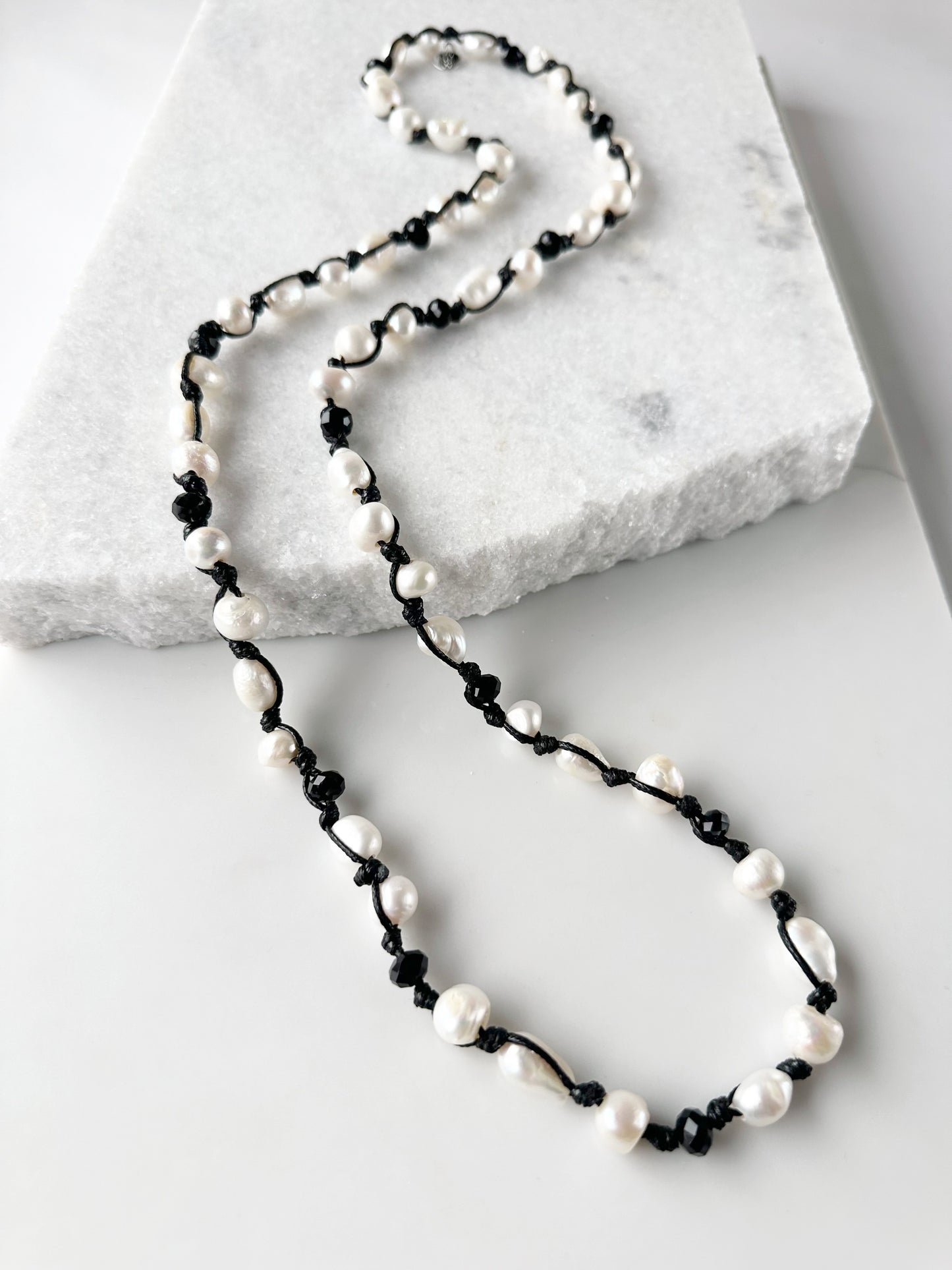 White Baroque Freshwater Pearls and Faceted Crystals Knotted on Black Cotton Cord on a 30” Necklace.