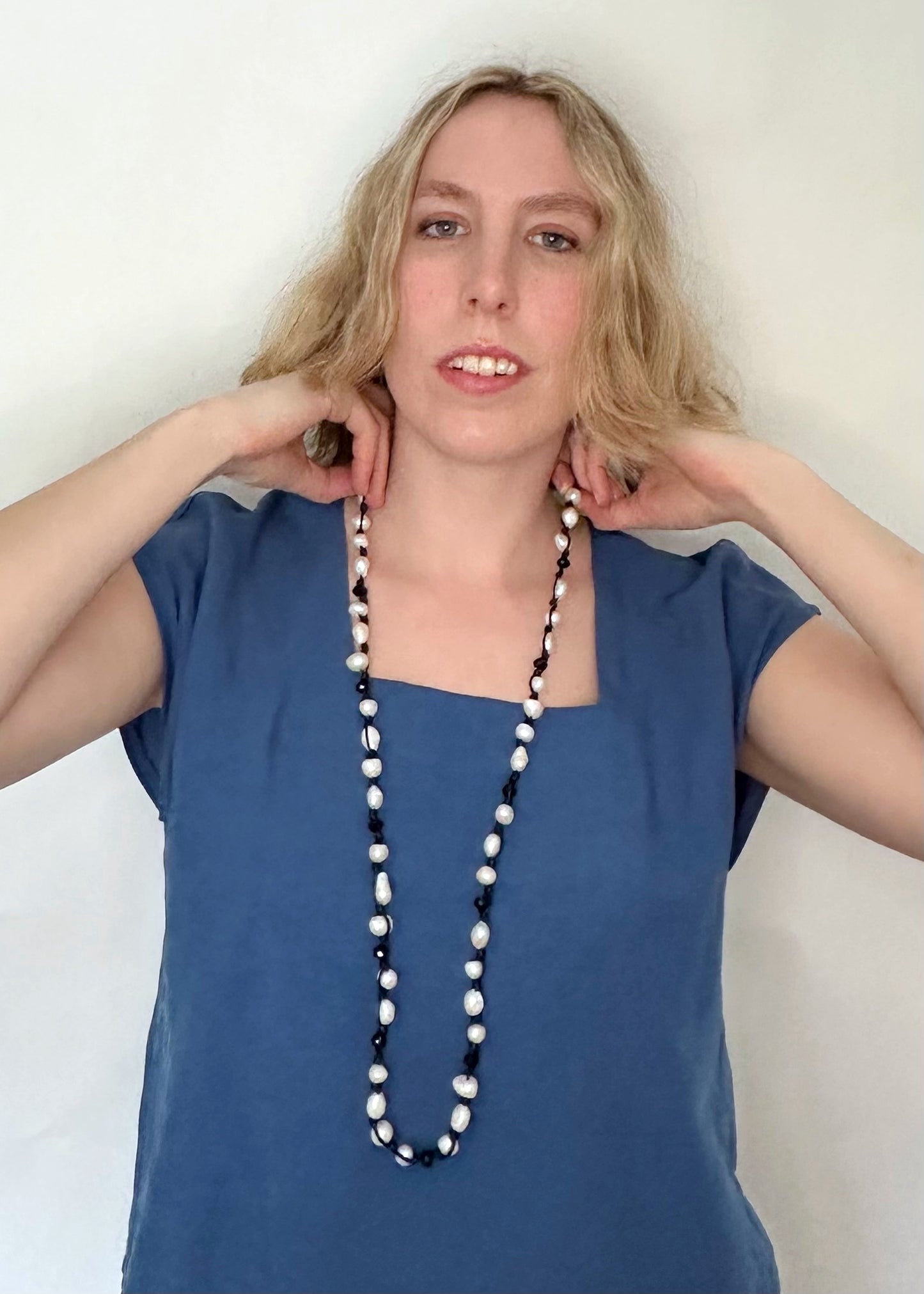 White Baroque Freshwater Pearls and Faceted Crystals Knotted on Black Cotton Cord on a 30” Necklace. On Model