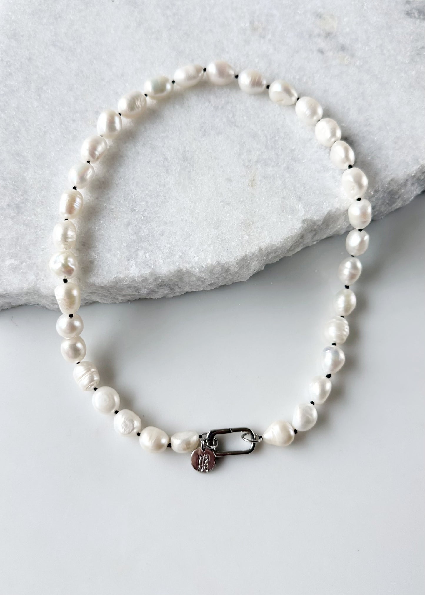 Lustrous Baroque Freshwater Pearls are Knotted in Black with a Silver Charm Clasp to Place your Favorite Pendants.  And Wear the 18.5” Necklace in Reverse to show off the Classic Pearls.