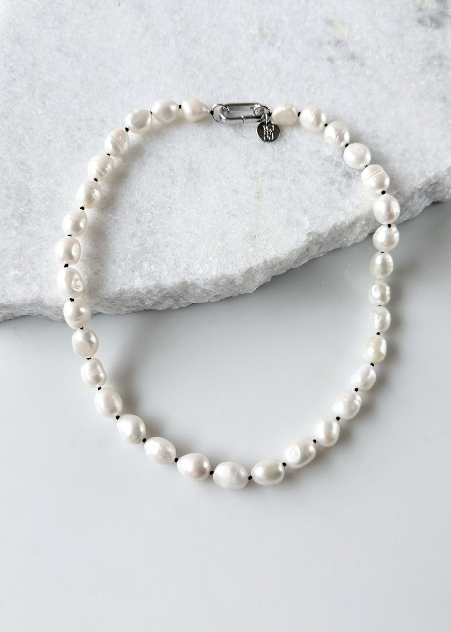 Lustrous Baroque Freshwater Pearls are Knotted in Black with a Silver Charm Clasp to Place your Favorite Pendants.  And Wear the 18.5” Necklace in Reverse to show off the Classic Pearls.