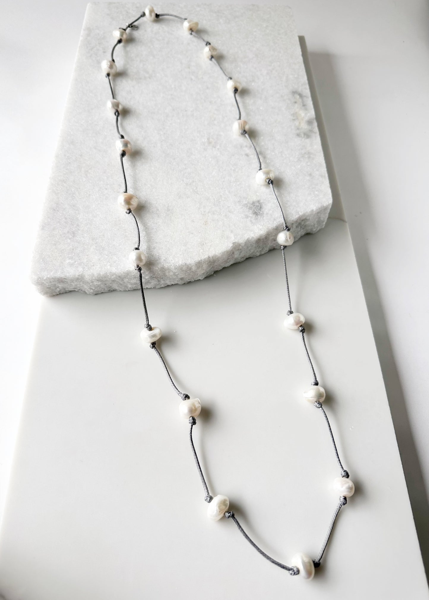 Lustrous White Freshwater Pearls  on Grey Cotton in this 21” Necklace.