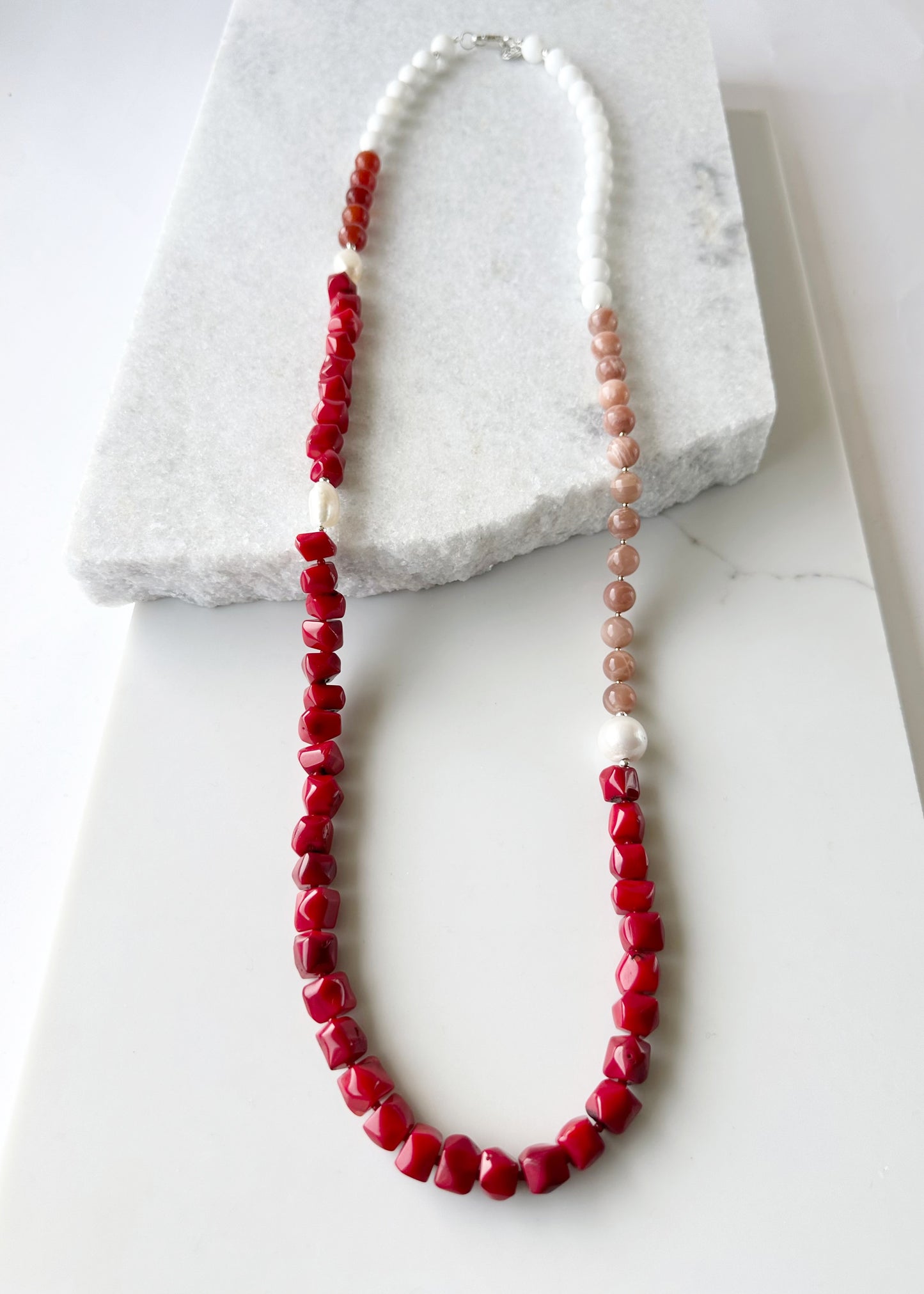 This 38” Long and Beautiful Necklace Boasts a Rich Blend of Colours including Vibrant Red Sea Bamboo, Soft Peach Moonstone, Faceted Carnelian, Crisp White Agate and Elegant White Freshwater Pearls.  The Necklace is finished with Gold and Silver Beads and a Sterling Silver Lobster Claw Clasp and can be Worn Long or Doubled Up.