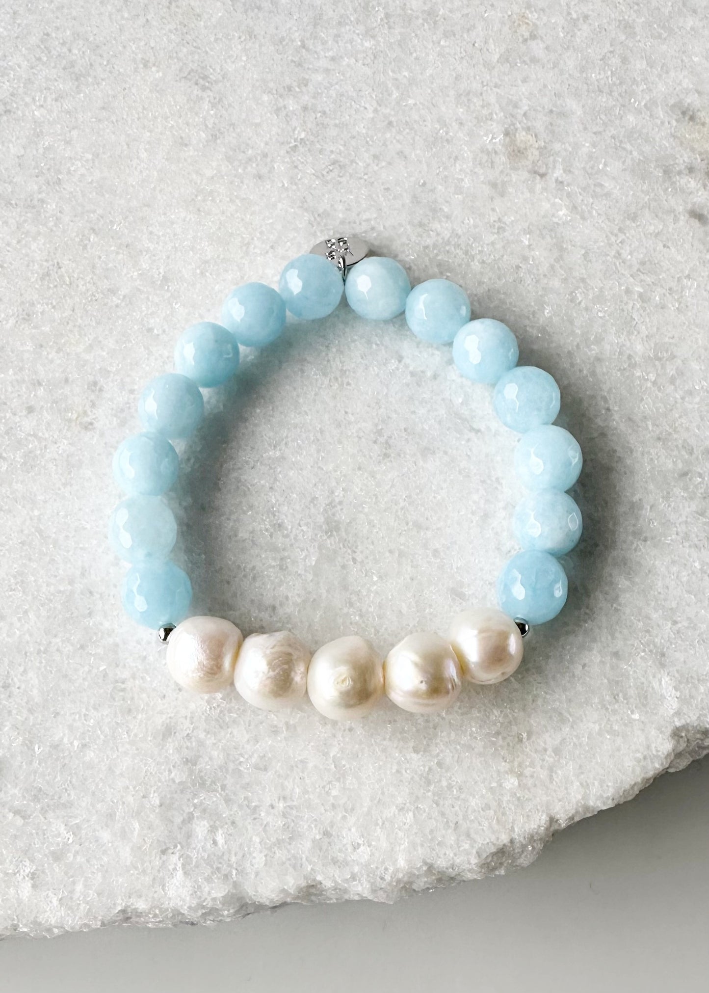 Five Large White Baroque Freshwater Pearls Accompanied by Light Blue Semi-Precious Stones (10 mm) with Silver accents in this 7” Stretch Bracelet.