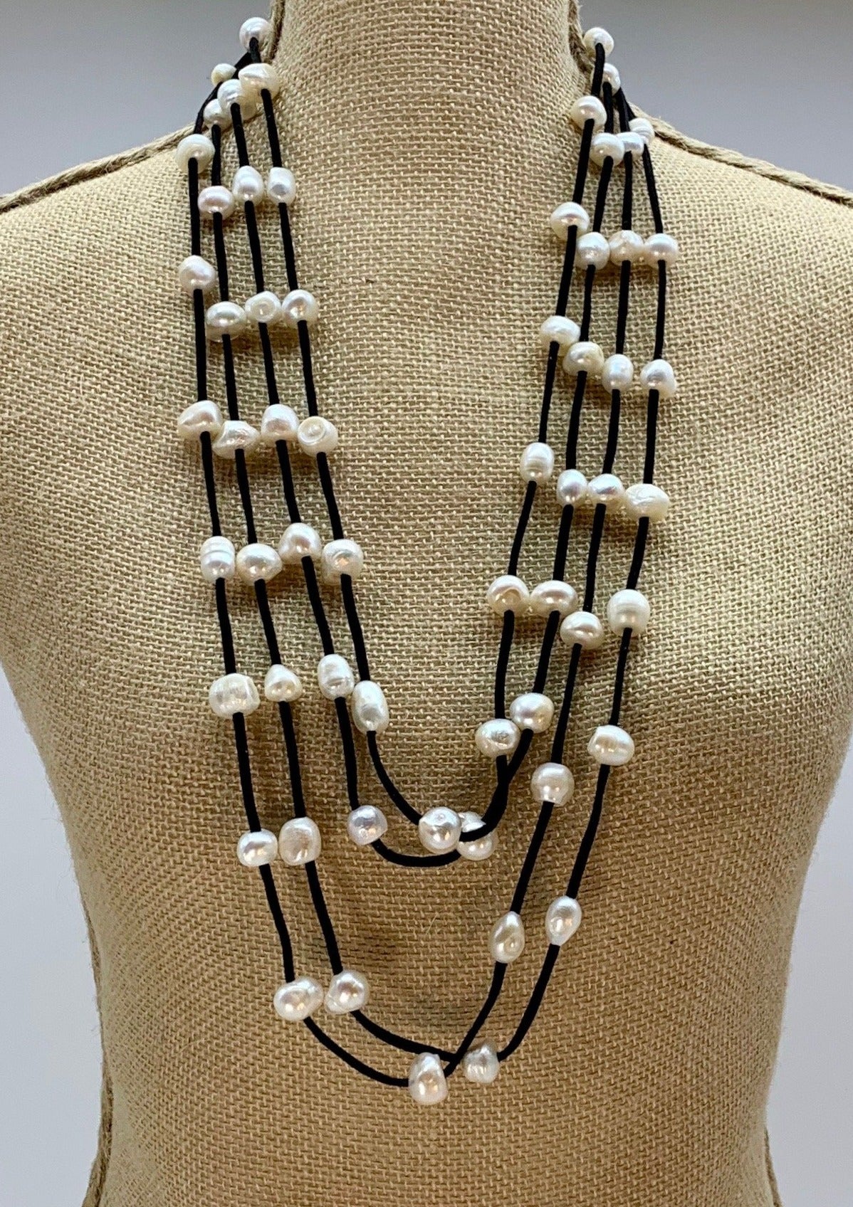 Four Strand Freshwater Pearl Necklace showing White Pearls Staggered on Black Vegan Suede.  A Strong, Secure Magnetic Clasp Makes this Easy to Put on and Take off. On Bust