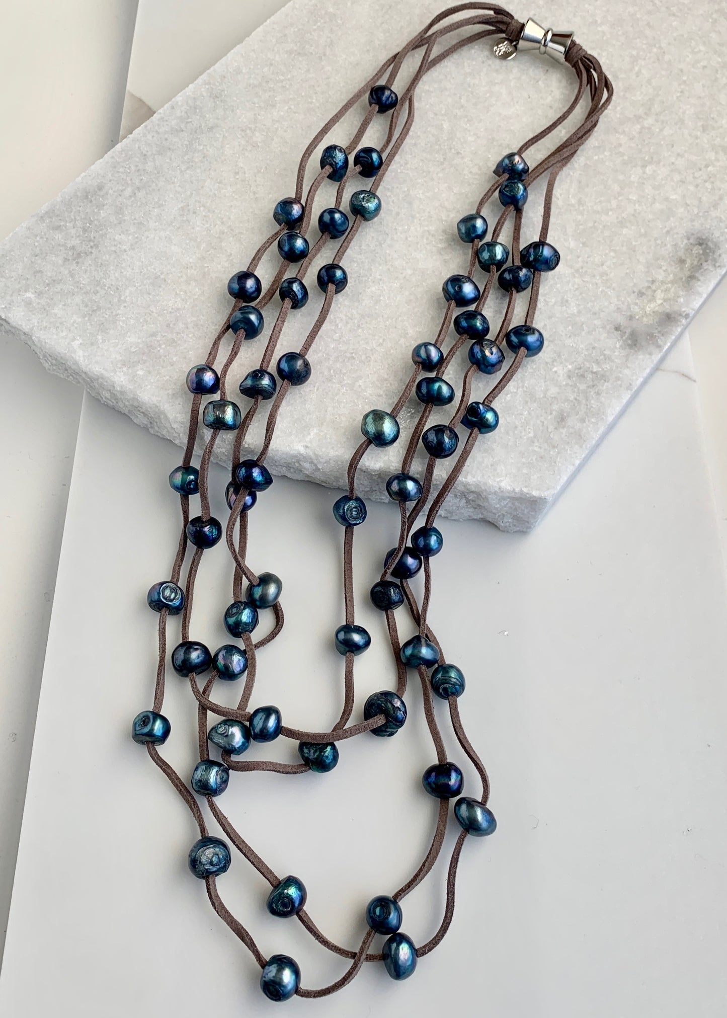 Four Strand Freshwater Pearl Necklace showing Blue Pearls Staggered on Grey Vegan Suede.  A Strong, Secure Magnetic Clasp Makes this Easy to Put on and Take off.