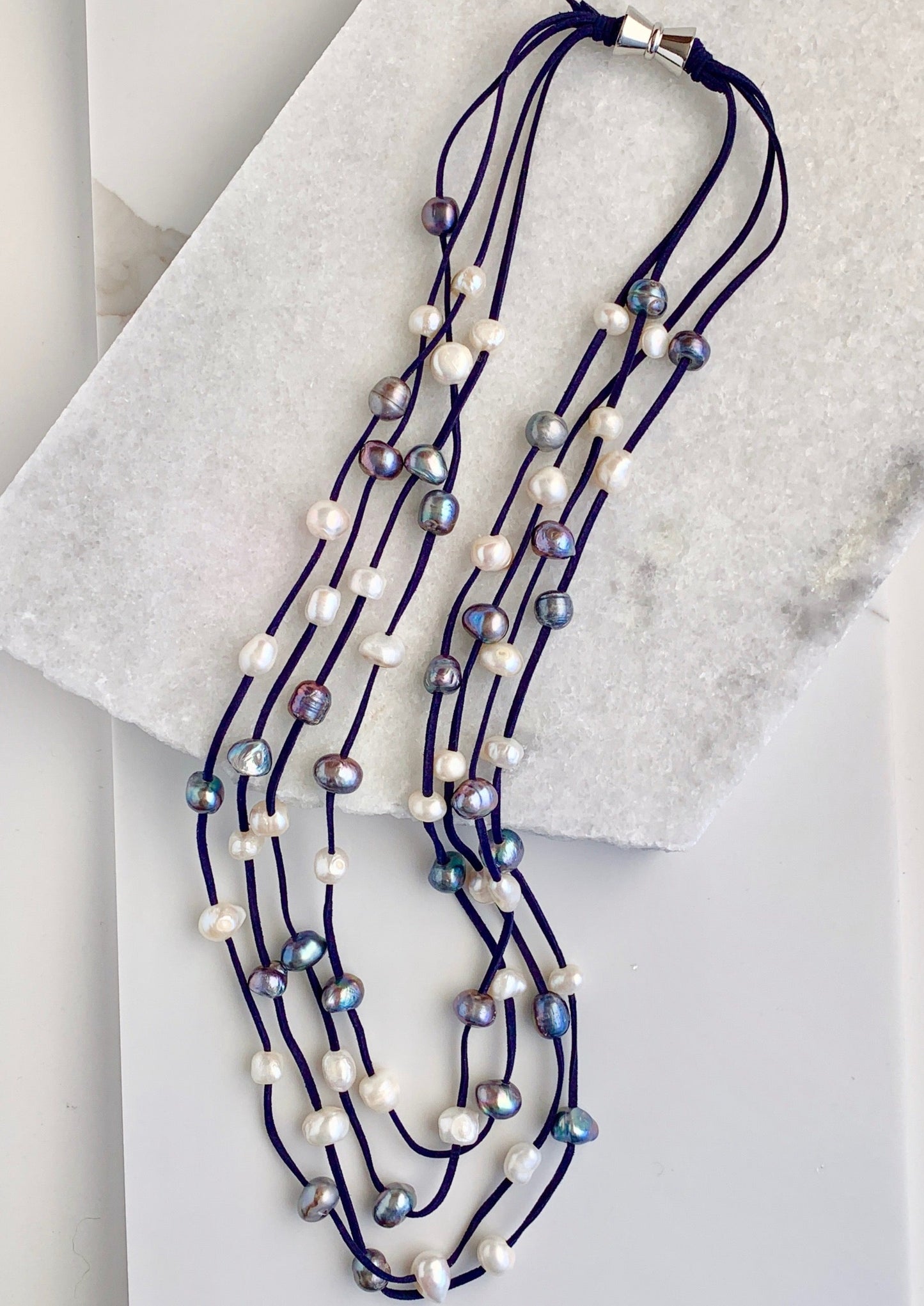 Four Strand Freshwater Pearl Necklace showing Mixed Pearls Staggered on Navy Vegan Suede.  A Strong, Secure Magnetic Clasp Makes this Easy to Put on and Take off.