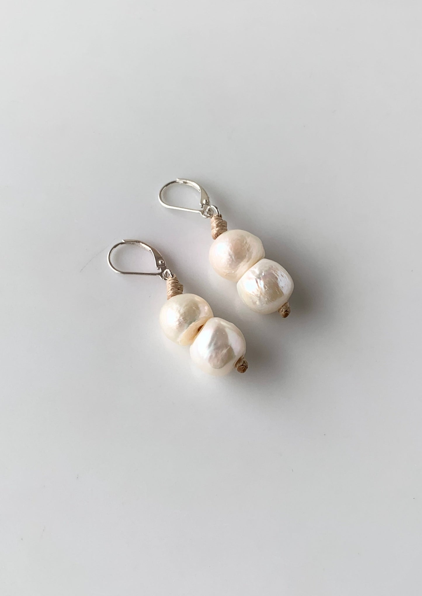 Two White Freshwater Pearls on a Sterling Siler Lever Back with Beige accent.
