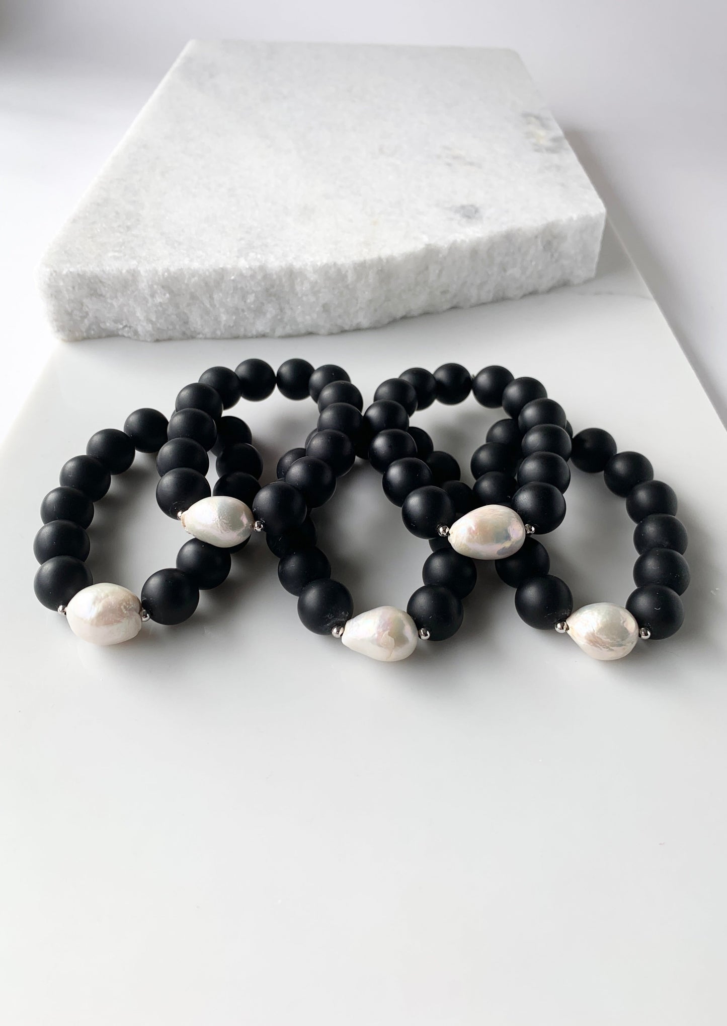 Stretch Bracelet Highlighting a Large White Baroque Freshwater Pearl with Silver Accents with Large (14mm) Matte Black Agate. Five Shown Together