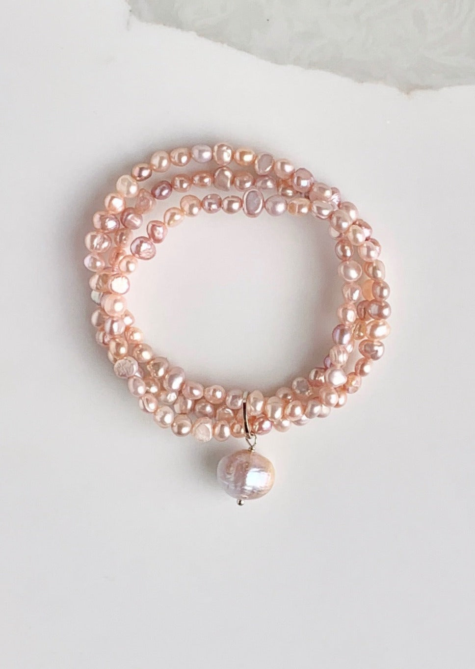 Three Strands of Delicate Pink Baroque Freshwater Pearls with a Large Pearl Dangle form this Pretty Stretch Bracelet.