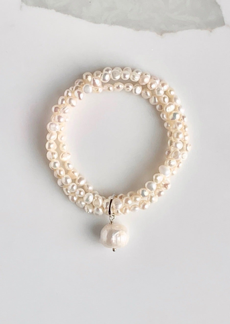 Three Strands of Delicate White Baroque Freshwater Pearls with a Large Pearl Dangle form this Pretty Stretch Bracelet.