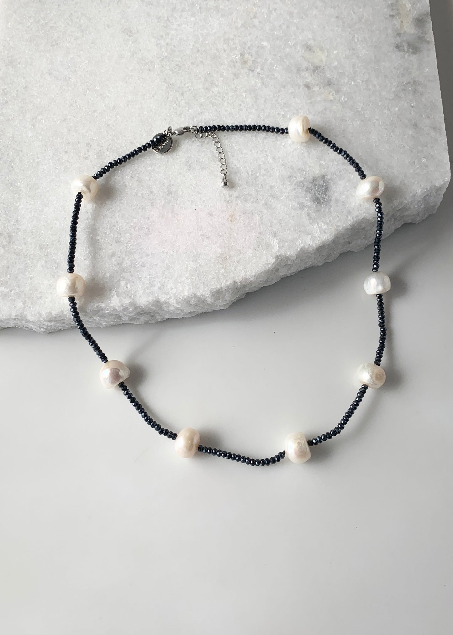 White Freshwater Pearls and Navy (2mm) Faceted Crystals form this 18” Necklace with 1.5” Extender.  The Piece is finished with a Lobster Claw Clasp.