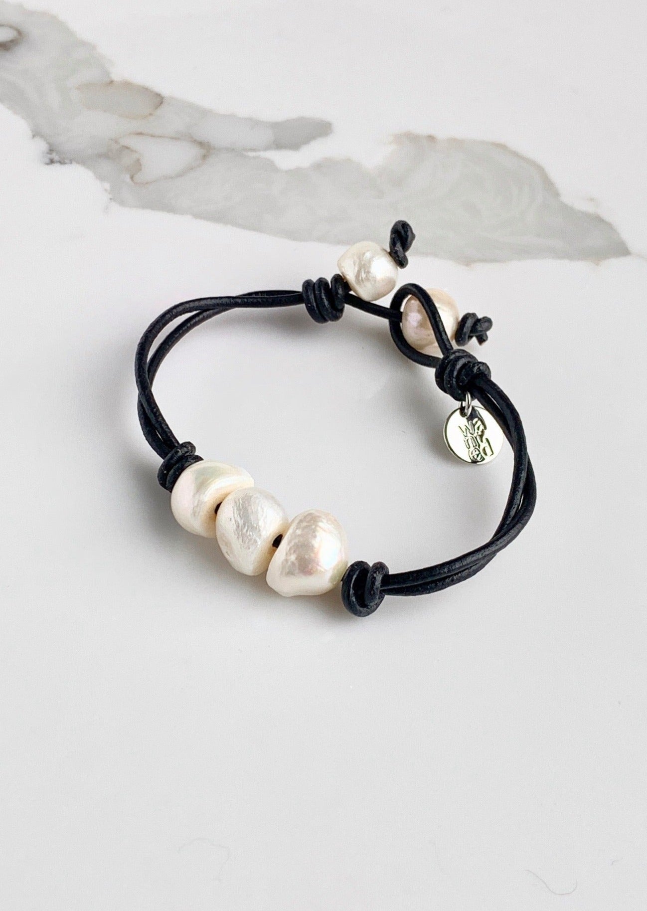 Black Leather Bracelet Highlighting Three White Baroque Freshwater Pearls with a Separate Pearl and Loop Closure. Can be worn Separately or Layered with other Bracelets.
