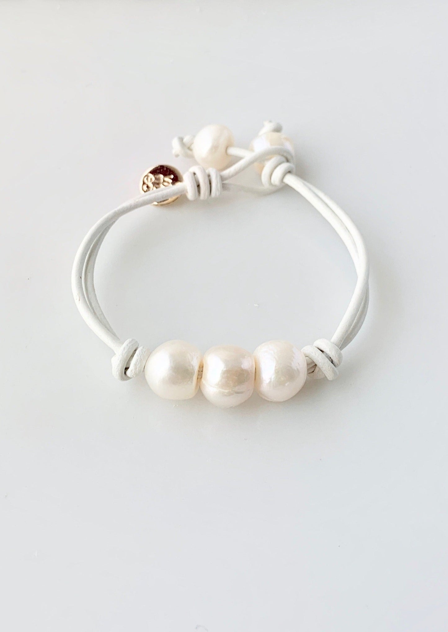 White Leather Bracelet Highlighting Three White Baroque Freshwater Pearls with a Separate Pearl and Loop Closure. Can be worn Separately or Layered with other Bracelets.