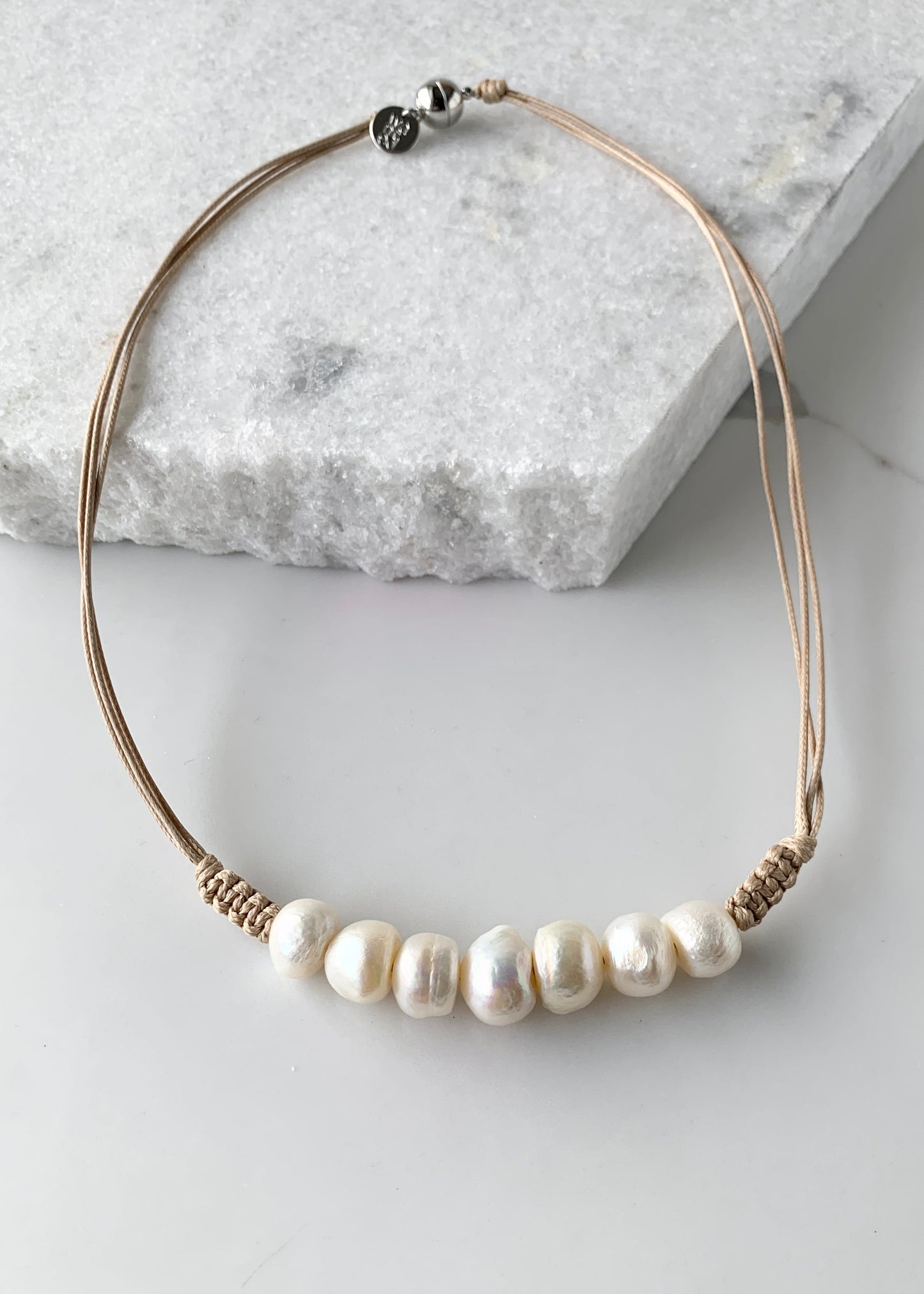 Seven Lustrous White Freshwater Baroque Pearls set on Beige Cotton Cord with a Hint of Decorative Knotting on this 20” Necklace.