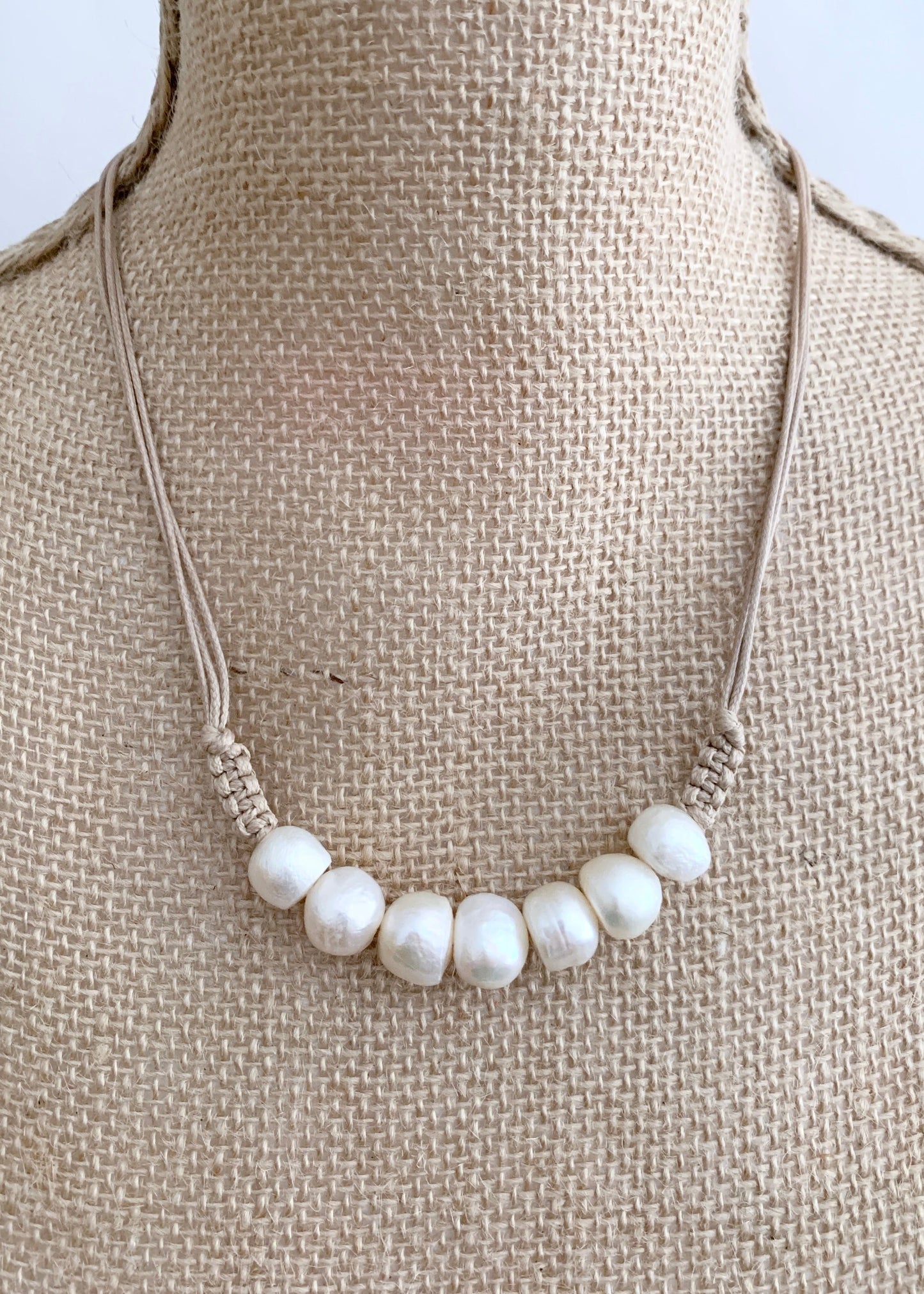 Seven Lustrous White Freshwater Baroque Pearls set on Beige Cotton Cord with a Hint of Decorative Knotting on this 20” Necklace. On Bust