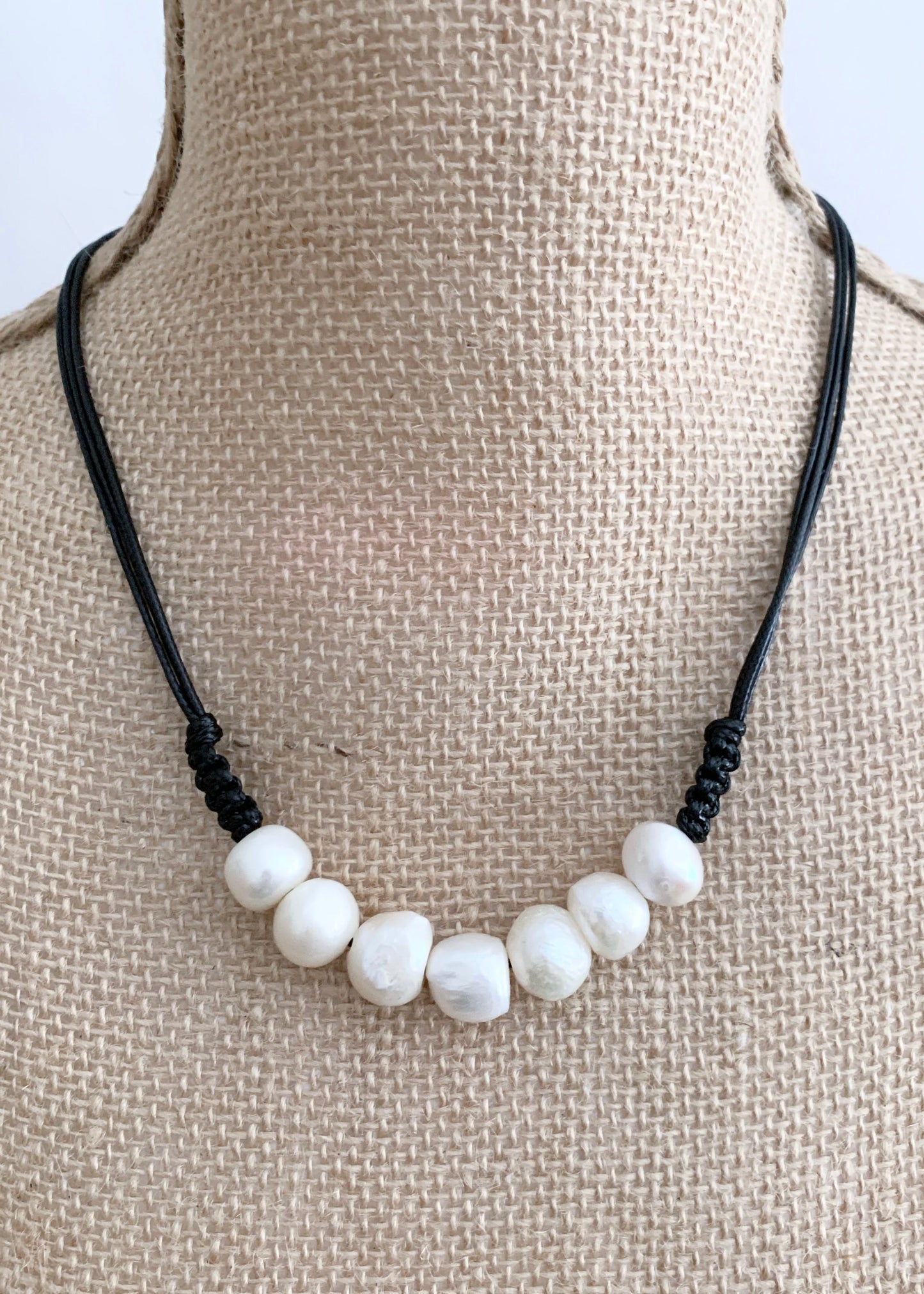 Seven Lustrous White Freshwater Baroque Pearls set on Black Cotton Cord with a Hint of Decorative Knotting on this 20” Necklace. On Bust