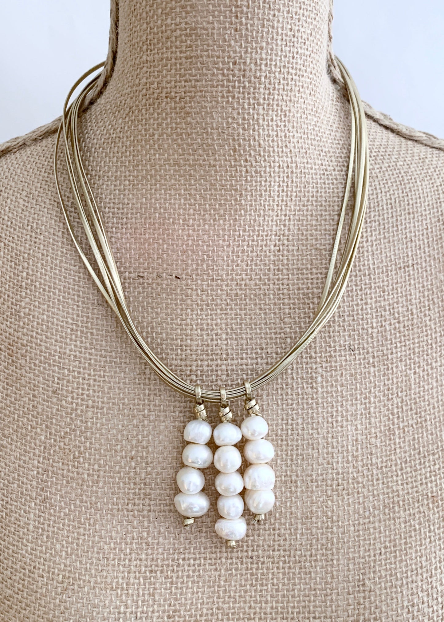 Three Stacks of White Baroque Freshwater Pearls on Gold Metal Cord Make Up this Necklace with a Strong Secure Magnetic Clasp for Easy Wear. On Bust