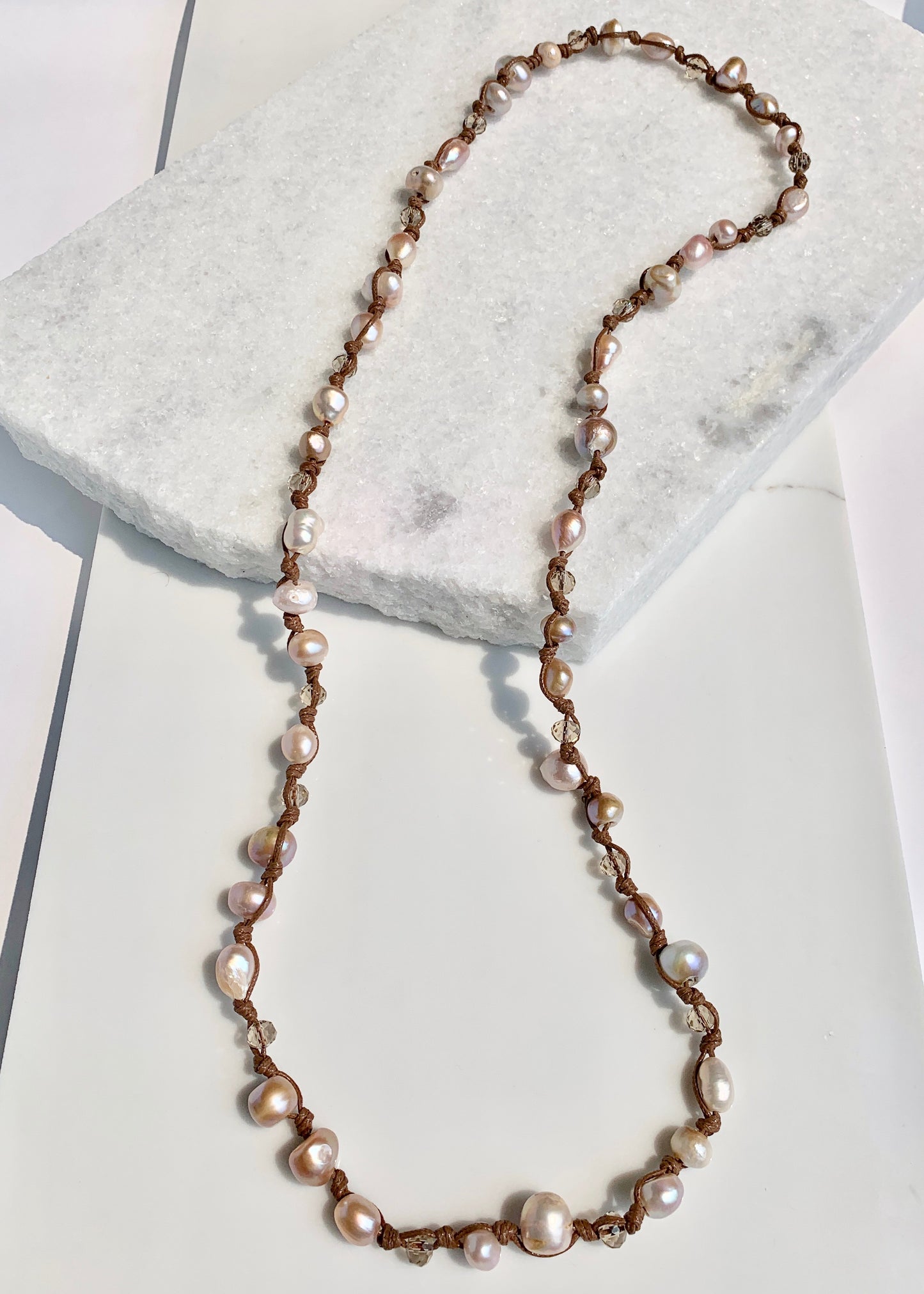 Lustrous Pink Baroque Freshwater Pearls and Faceted Crystals Knotted on Brown Cotton Cord on a 30” Necklace.