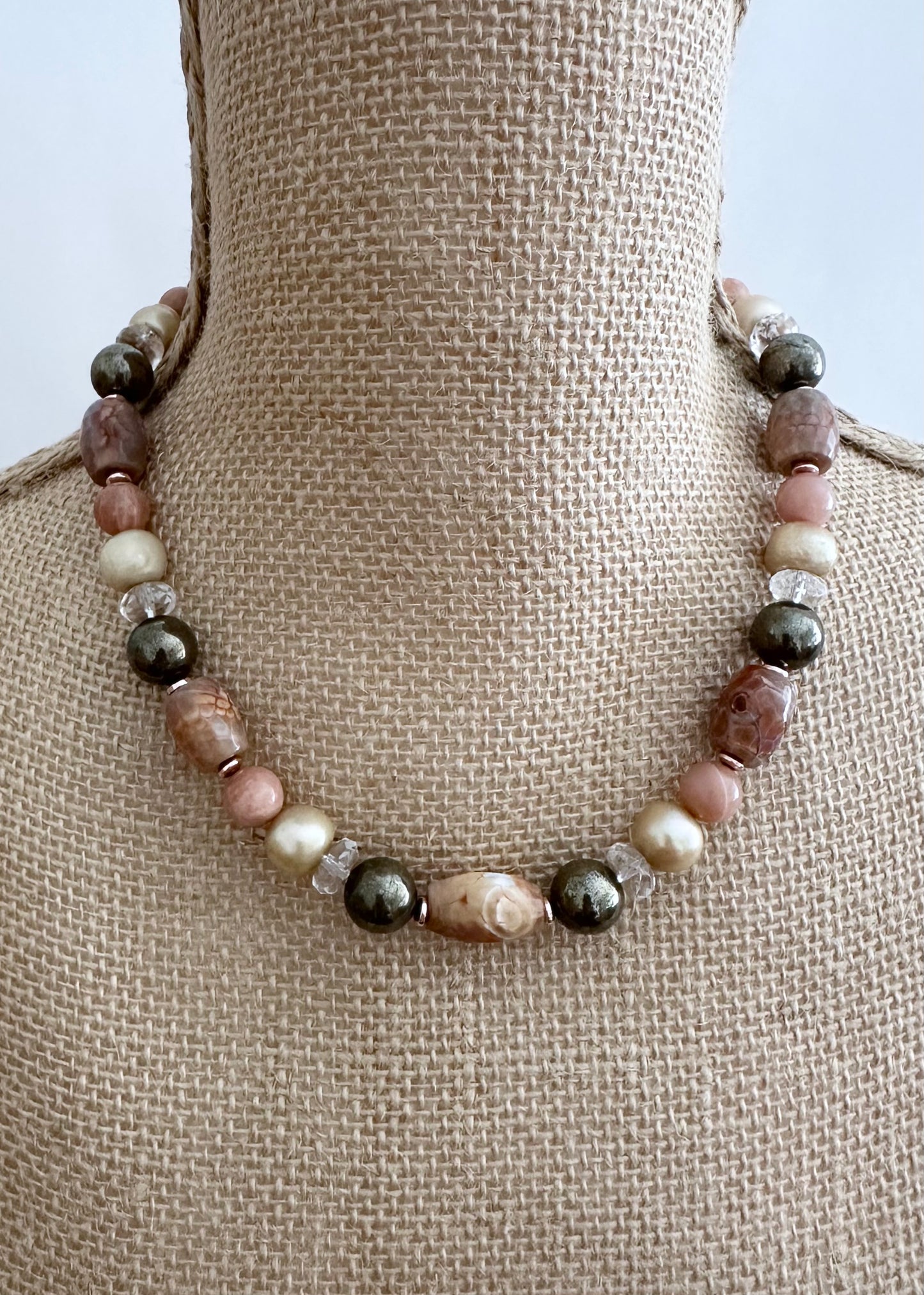 Designed and made in Canada, this beautiful One-Of-A-Kind 18.5” Necklace has Peach/Gold Tones with Faceted Agate Barrels, Large Pyrite Rounds, Faceted Clear Quartz, Moonstone and Lustrous Gold Freshwater Pearls. This piece is Finished with Gold-filled Lobster Claw Clasp and Rose Gold-Plated Hematite.
