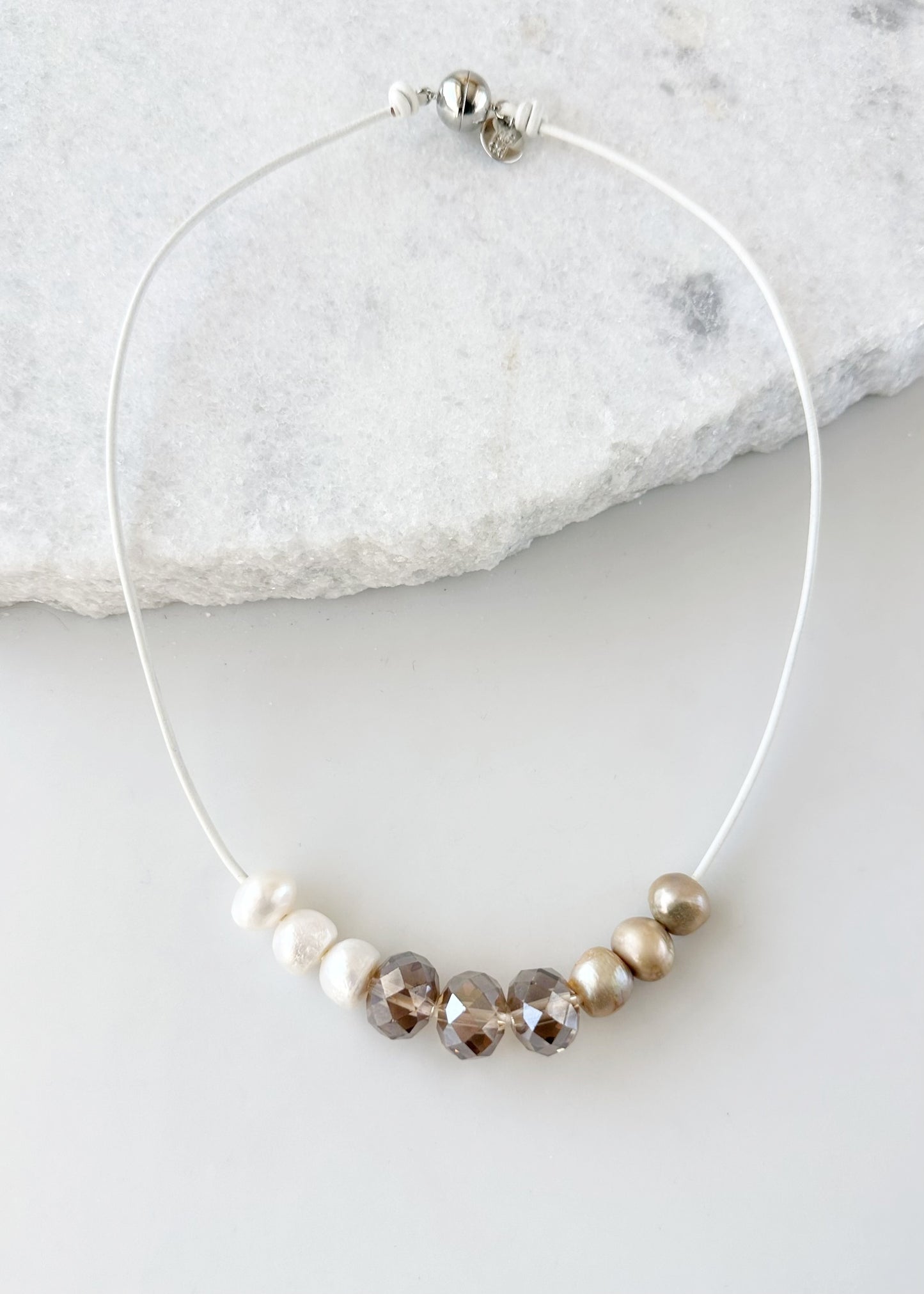 Designed in Canada, the 20” Carly Necklace gives a fun casual look with Three Large 16mm Crystals (Smoke or Champagne) surrounded by Pearls Floating on leather. It's Finished with a Magnetic Clasp for Easy Wear.