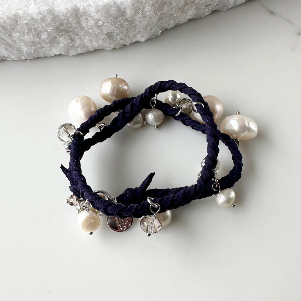 
                      
                        White and Champagne Baroque, Freshwater Pearls hang from this 14” Double Wrap Bracelet made of Vegan Suede in Navy.  The piece is completed with crystal accents and a Strong Secure Magnetic Clasp for Easy Wear.
                      
                    