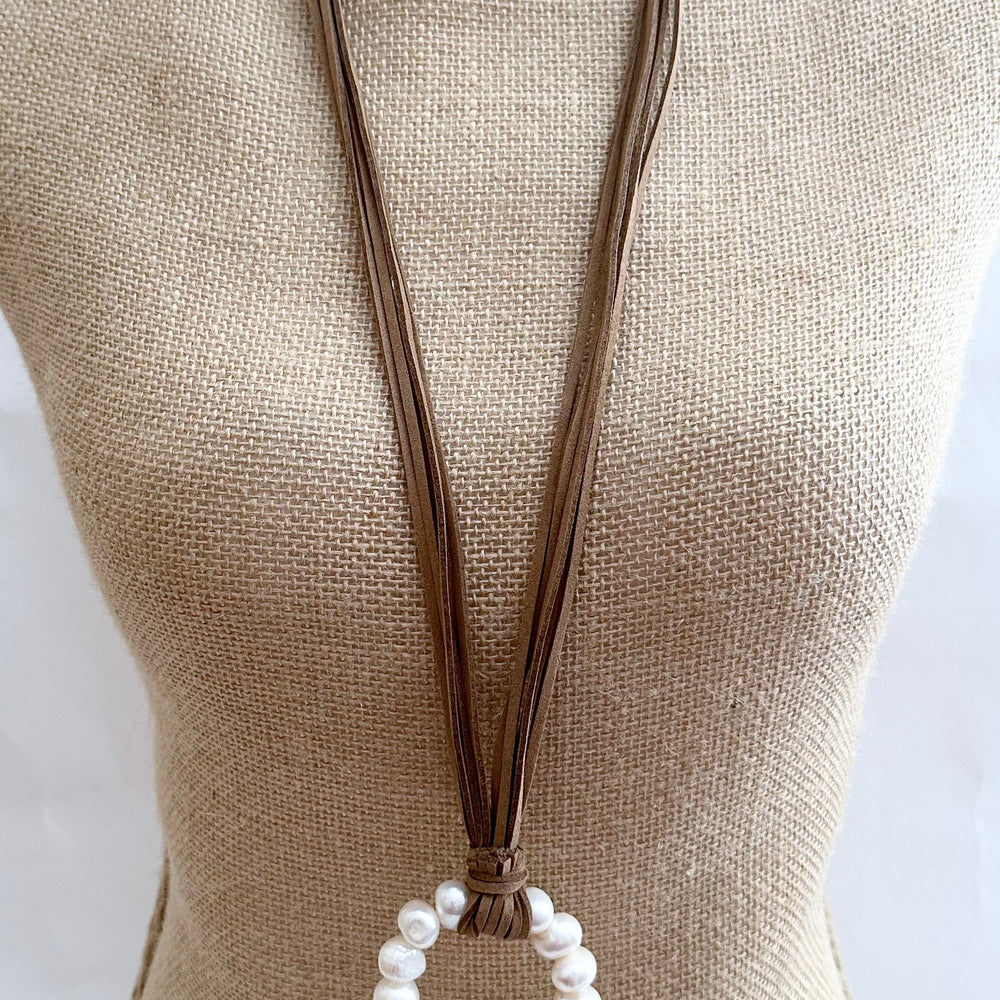 
                      
                        Necklace in Beige Vegan Suede Displaying a Large Ring Pendant of White Freshwater Pearls. On Bust
                      
                    