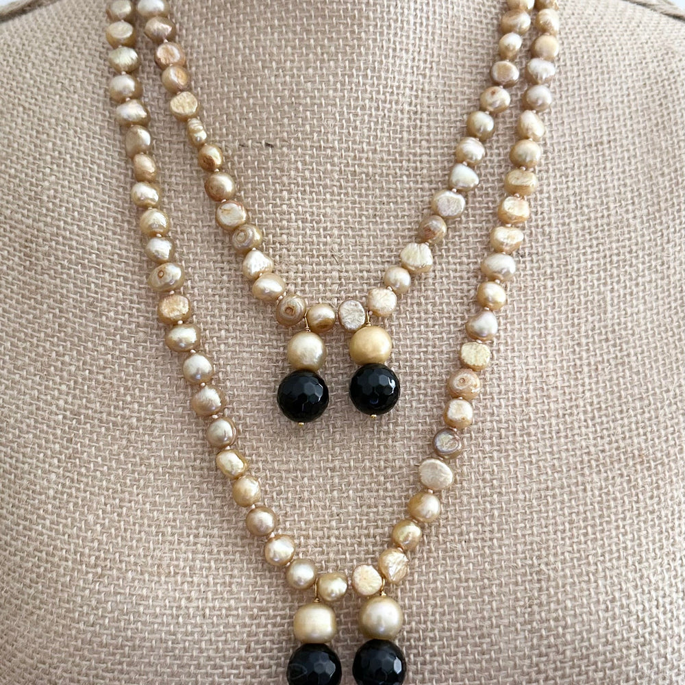 
                      
                        Long Generous Gold Freshwater Pearl Necklace with Larger Pearl and Black Agate drops.  Can be worn in many Styles. 
                      
                    