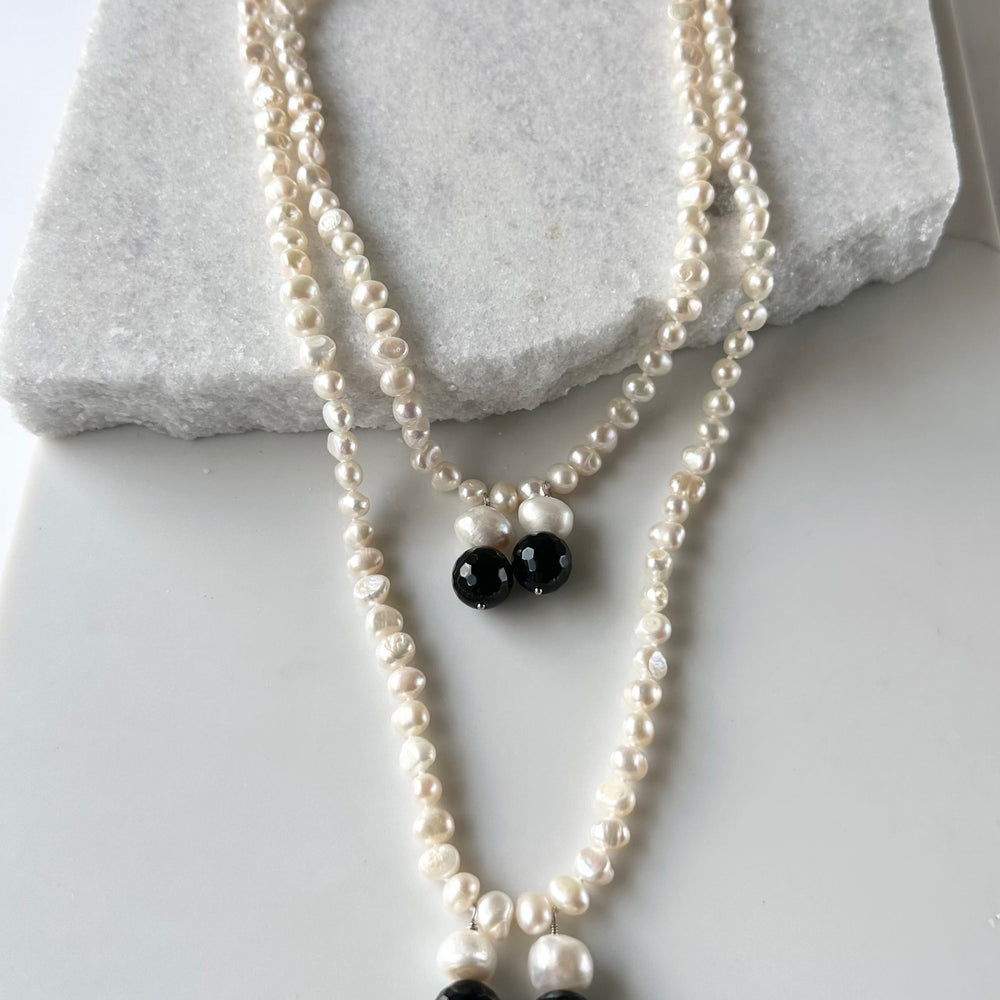 
                      
                        Long Generous White Freshwater Pearl Necklace with Larger Pearl and Black Agate drops.  Can be worn in many Styles. 
                      
                    