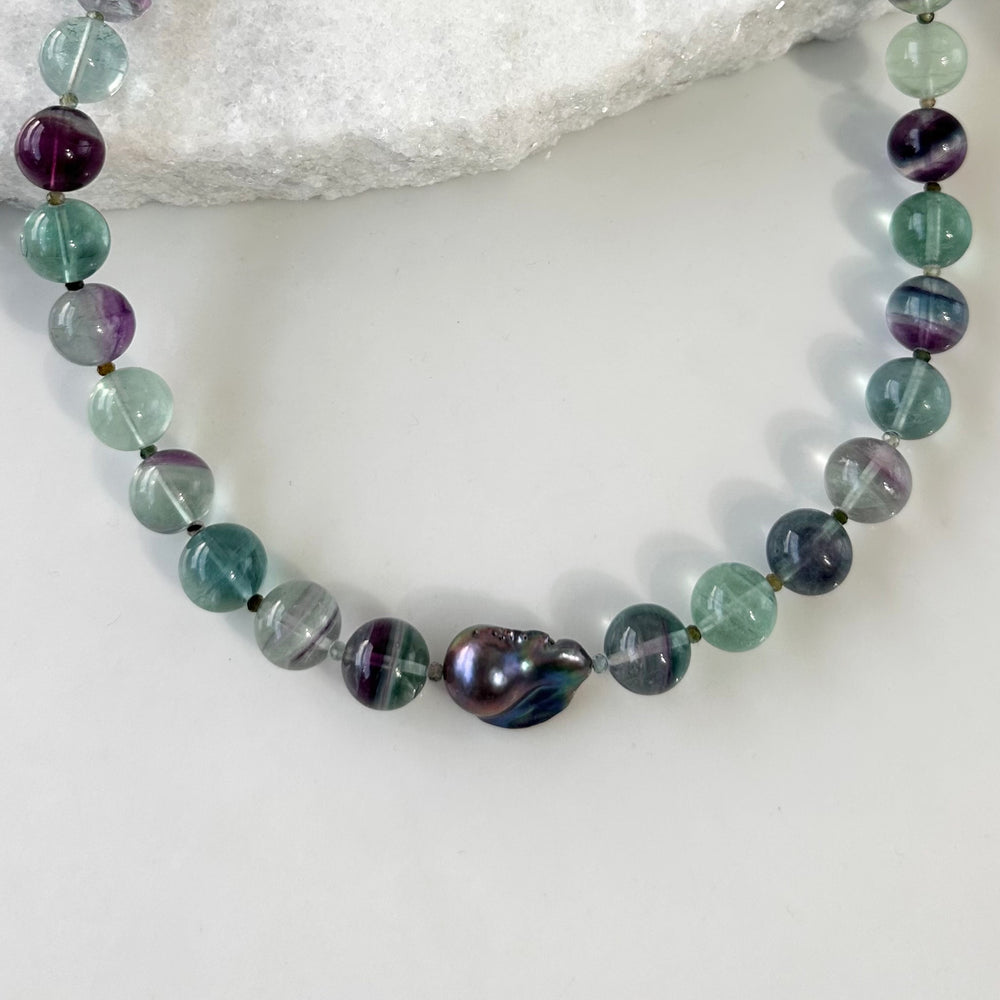
                      
                        Designed and Made in Canada, this unique 20.5” Necklace features Striking Large Round Fluorite, Delicate Faceted Tourmaline, and a Stunning Peacock Baroque Pearl, creating an exquisite blend of vibrant colours. The piece is finished with a Sterling Silver Lobster Claw Clasp.
                      
                    