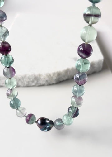 Designed and Made in Canada, this unique 20.5” Necklace features Striking Large Round Fluorite, Delicate Faceted Tourmaline, and a Stunning Peacock Baroque Pearl, creating an exquisite blend of vibrant colours. The piece is finished with a Sterling Silver Lobster Claw Clasp.