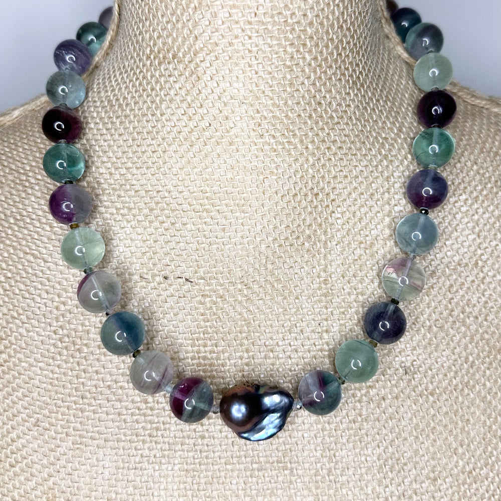 
                      
                        Designed and Made in Canada, this unique 20.5” Necklace features Striking Large Round Fluorite, Delicate Faceted Tourmaline, and a Stunning Peacock Baroque Pearl, creating an exquisite blend of vibrant colours. The piece is finished with a Sterling Silver Lobster Claw Clasp.
                      
                    