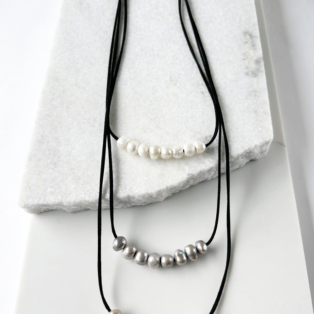 
                      
                        Three Strands of Black Vegan Suede with Floating White Silver and Gold Freshwater Pearls Completed with a Strong Secure Magnetic Clasp for Easy Wear.
                      
                    
