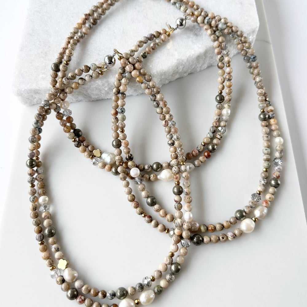 
                      
                        This Two-Strand (Inner Length of 19”) Necklace Features White African Opal and Freshwater Pearls Accented with Pyrite, Faceted Crystal and Gold-Plated Hematite for a soft elegant touch. Finished with a Magnetic Clasp for Easy Wear. Designed and made in Canada
                      
                    