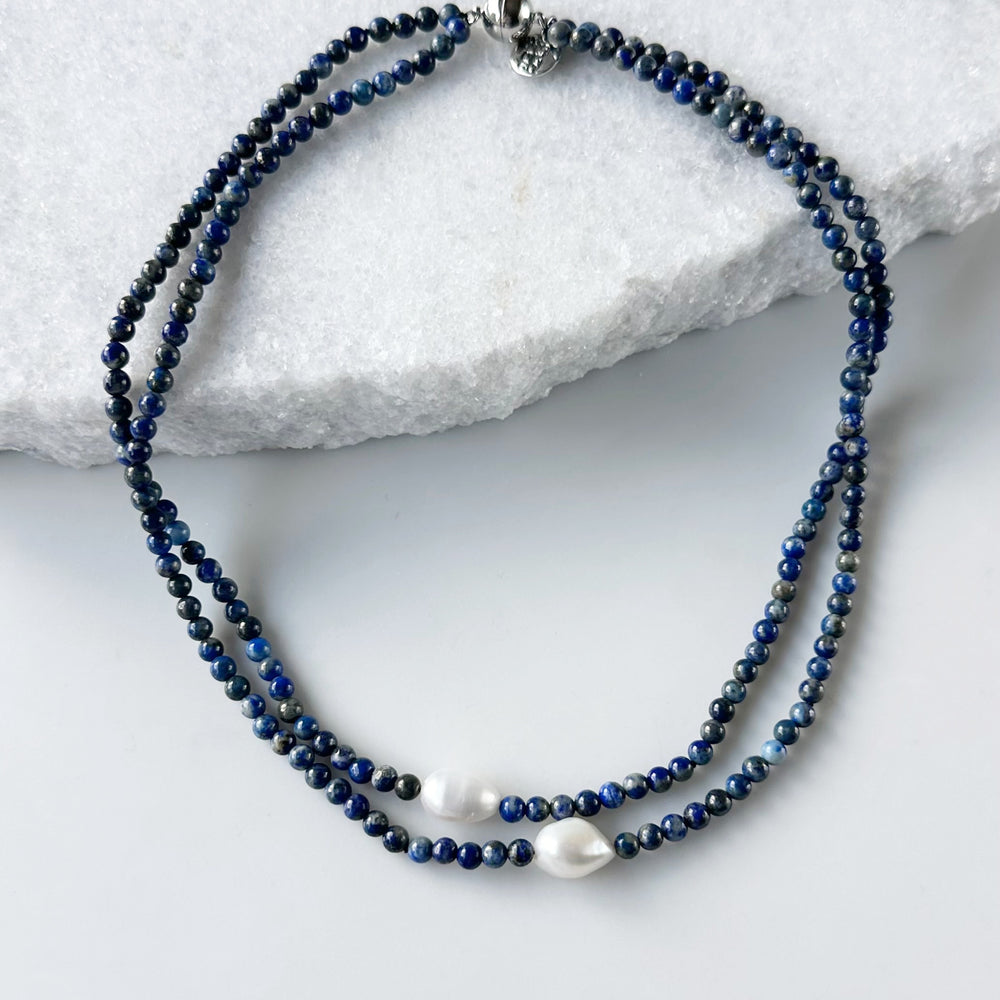 Beaded necklace with blue and white beads on a marble surface